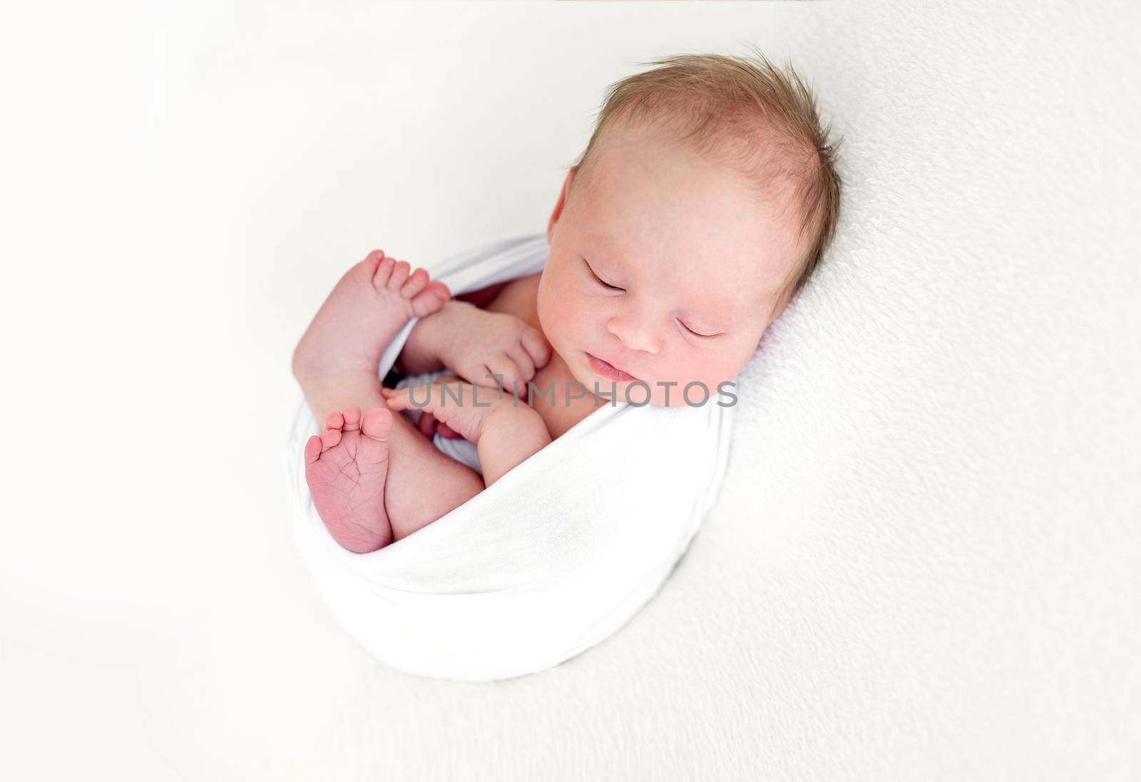 Sleeping newborn baby girl wrapped in white blanket