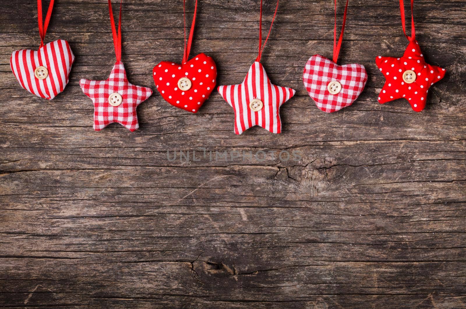 White and red sewed christmas decor attached to the rope, over wooden background