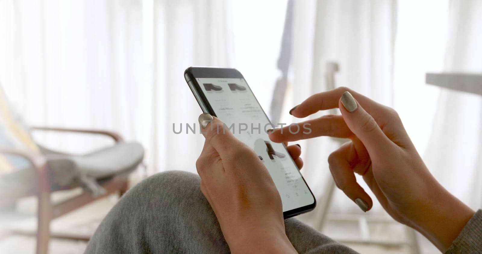 Woman browsing smartphone screen ordering clothes at home online