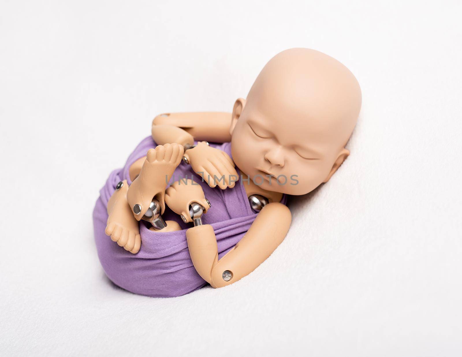 Beatiful doll of newborn kid in pouch sling for professional photo, on white background