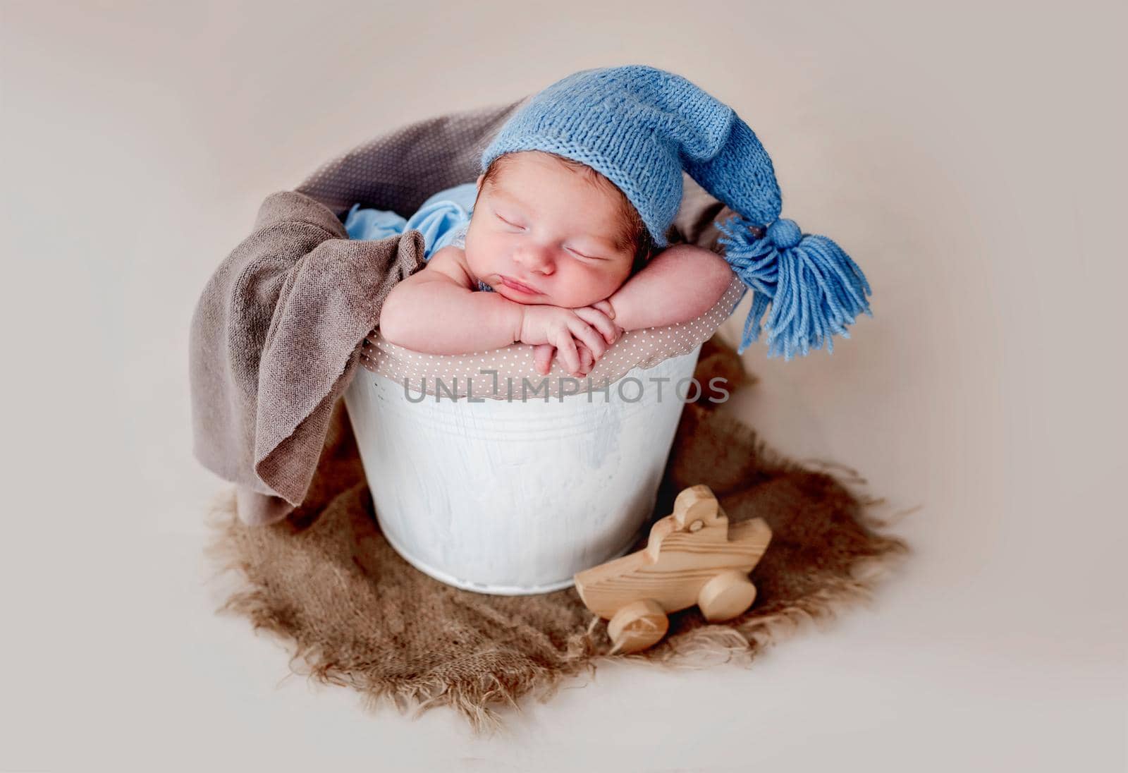 Funny newborn wearing blue knitted hat and resting in busket