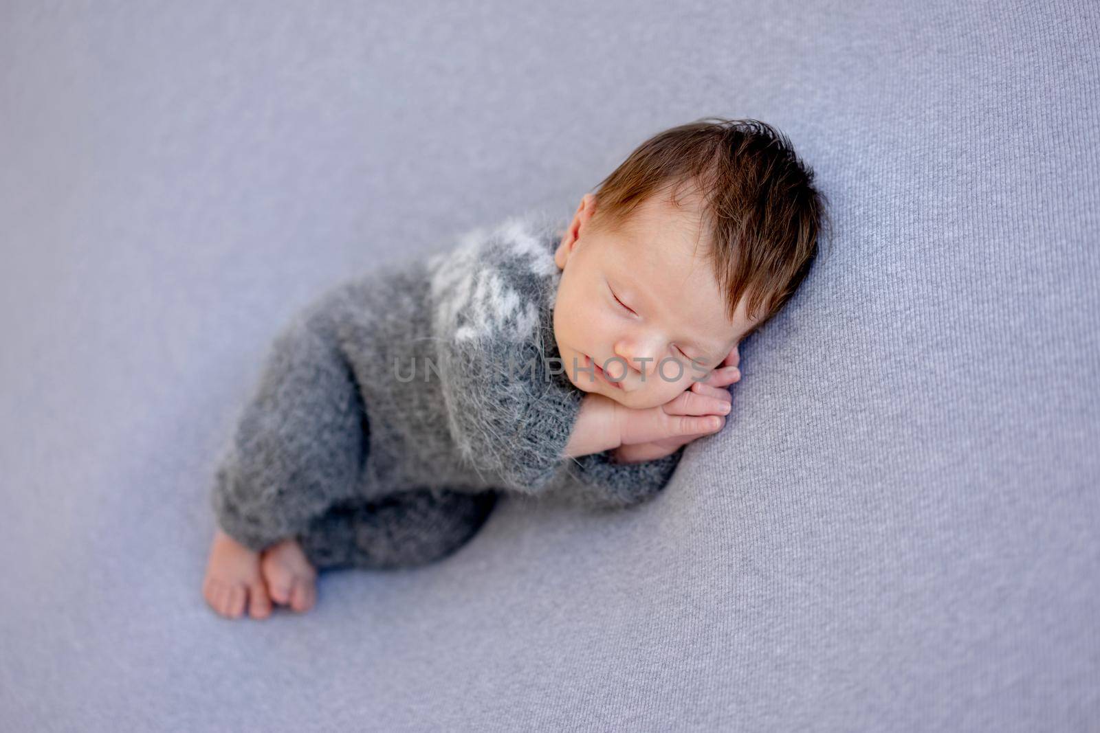 Lovely newborn in knitted suit sleeping on side