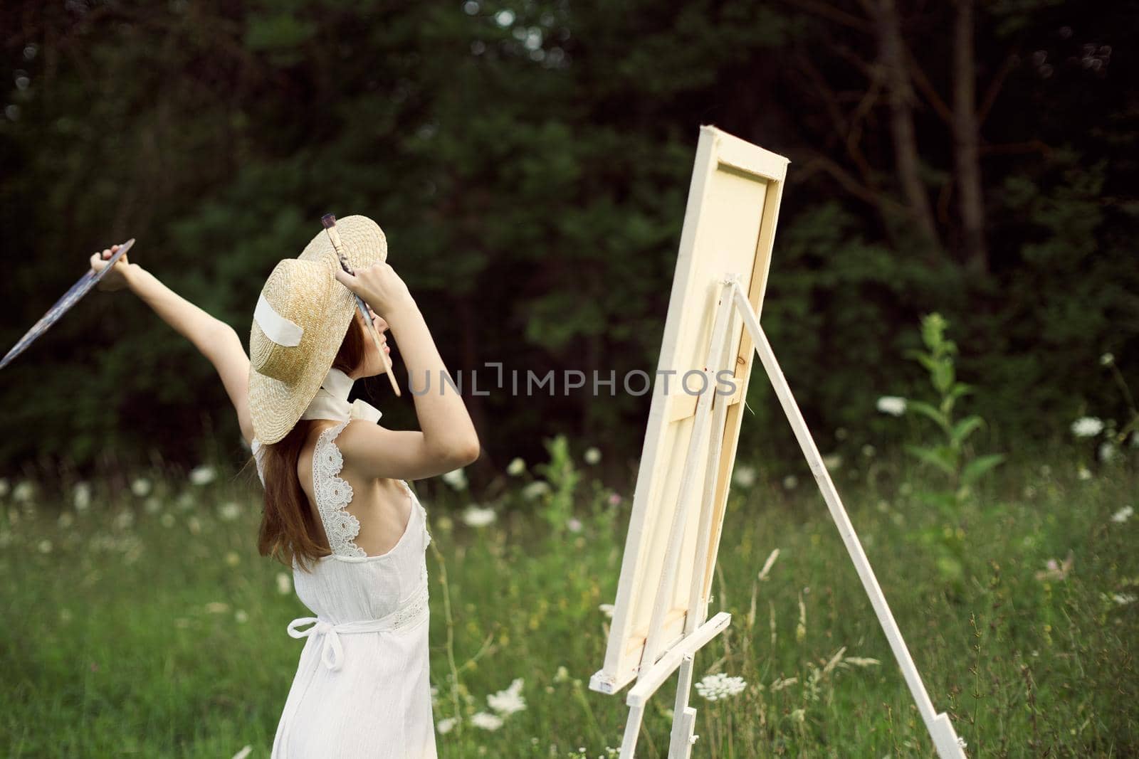 pretty woman artist paints a picture on nature landscape. High quality photo