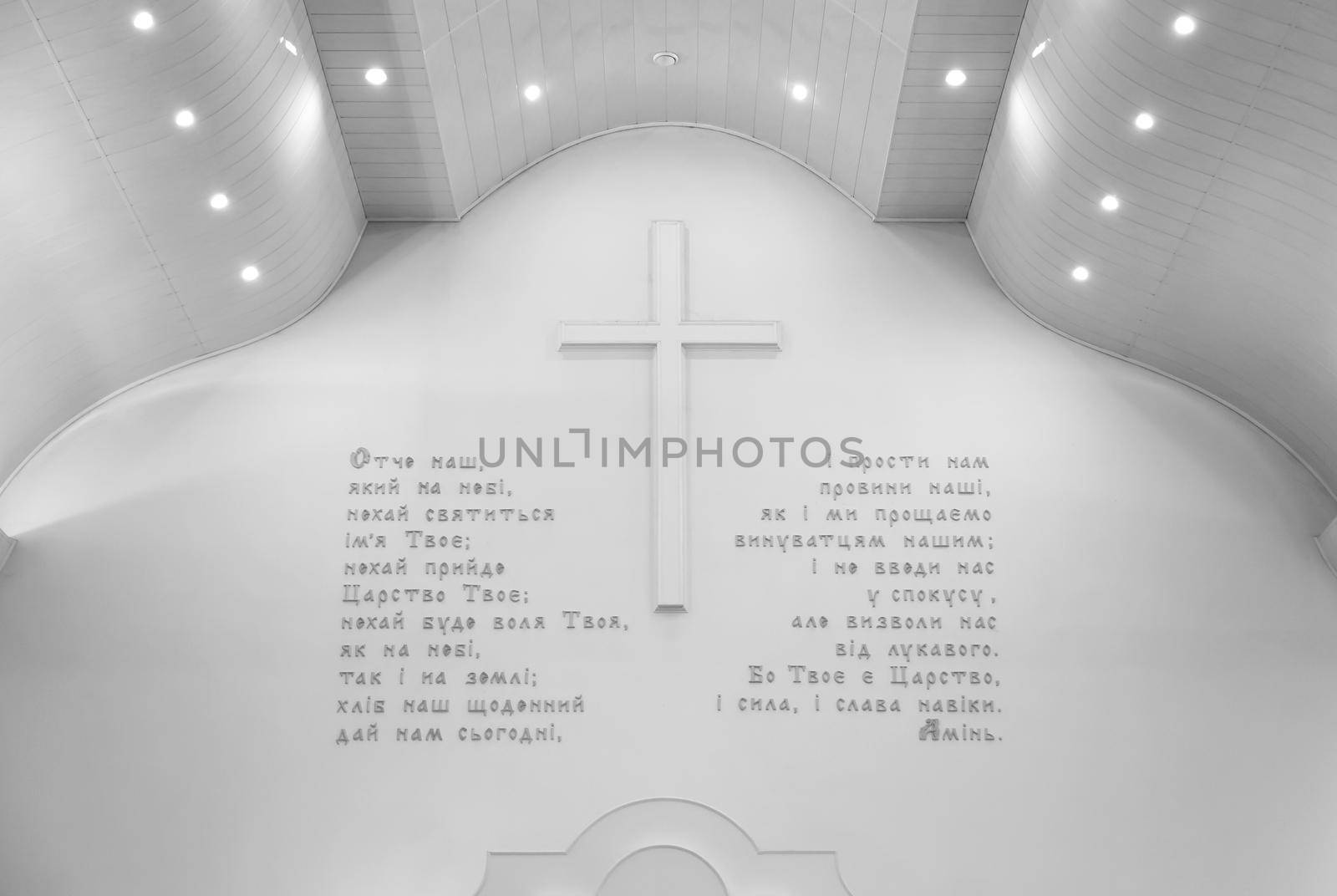 Bible theme. Prayer Our Father in Ukrainian on a white wall with a large cross