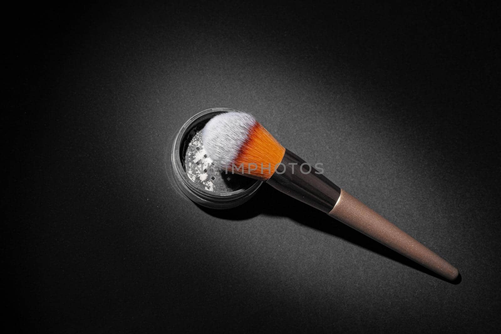 Make up powder with brush on black background, close up