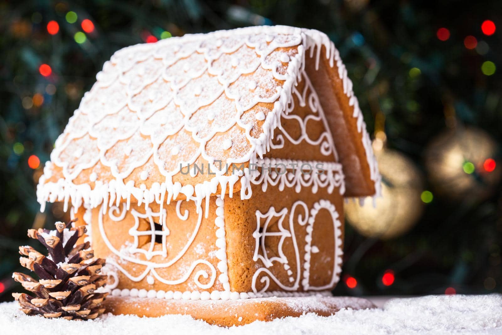 gingerbread house over defocused lights of Chrismtas decorated fir tree