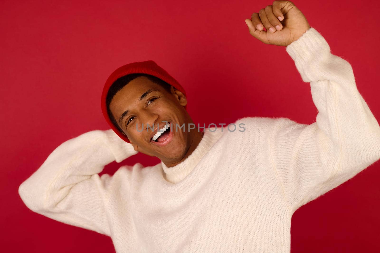 Young dark-skinned man in santa hat smiling by SDM_Prod_Studio