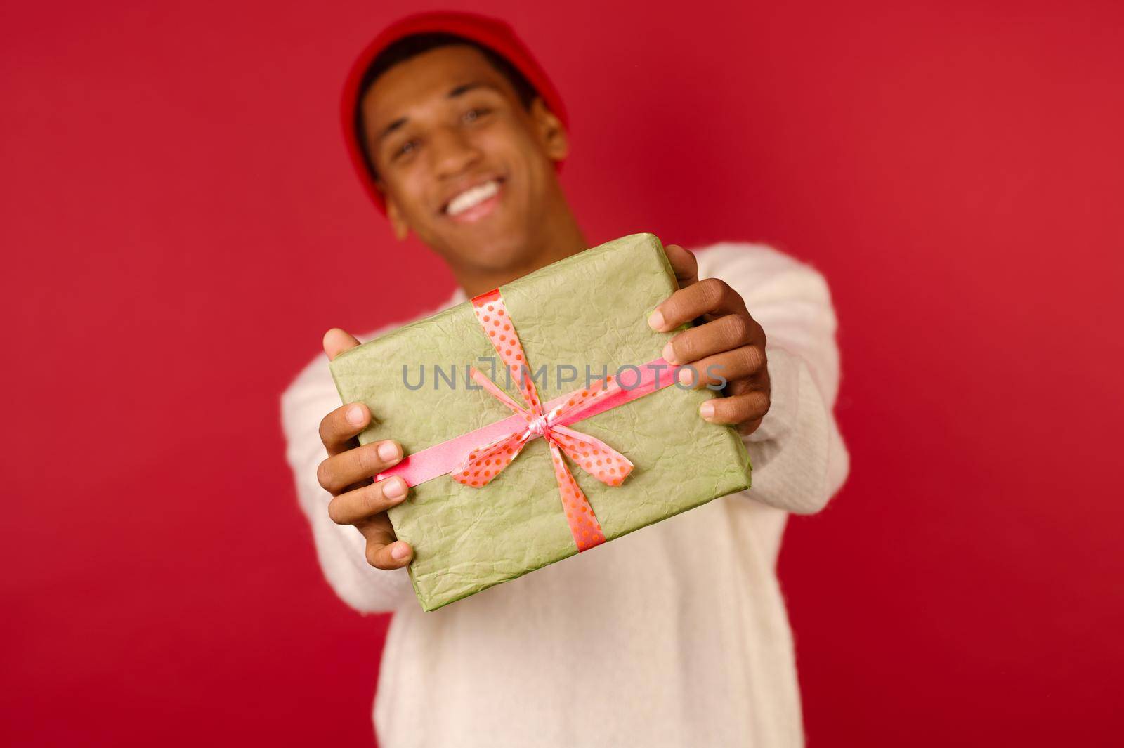 Xmas present. A dark-skinned young guy with a gift box in hands