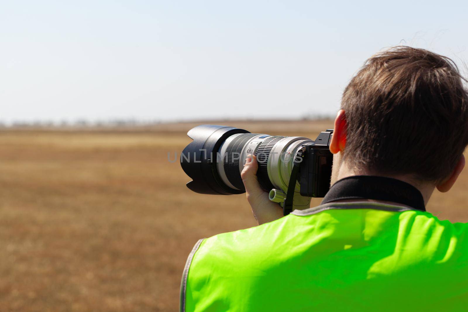 Man in yellow vest does plane spotting at the airport, close up