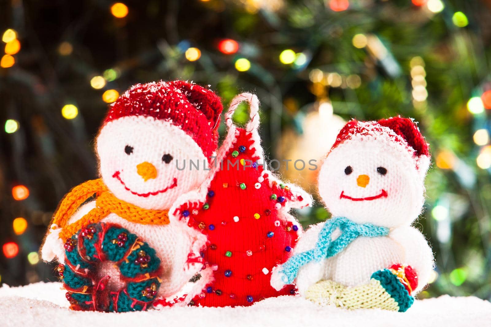 Knitted snowmen and handmade Christmas tree - home decorations on the snow