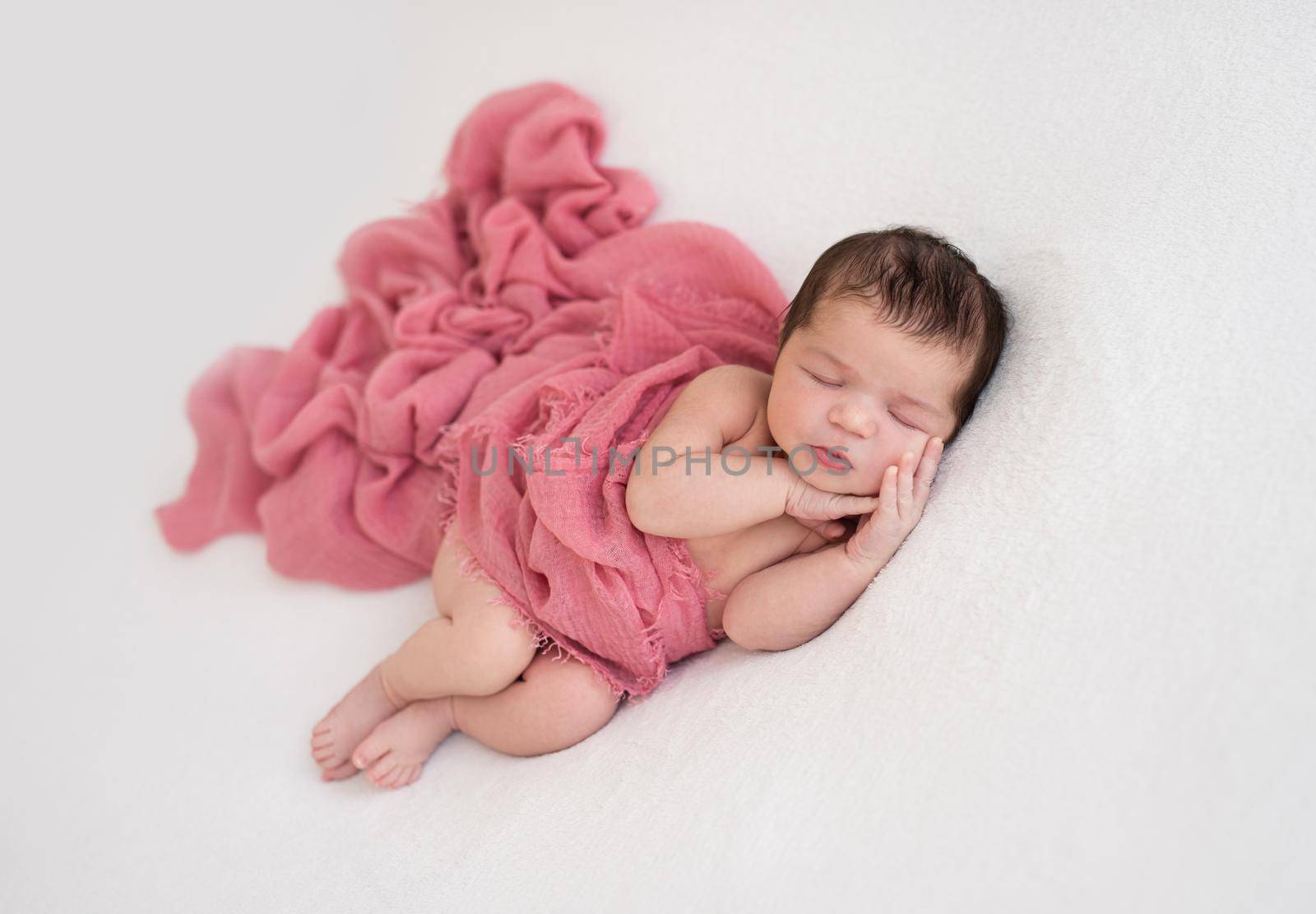 Beautiful sleeping newborn lying on side lightly covered with blanket