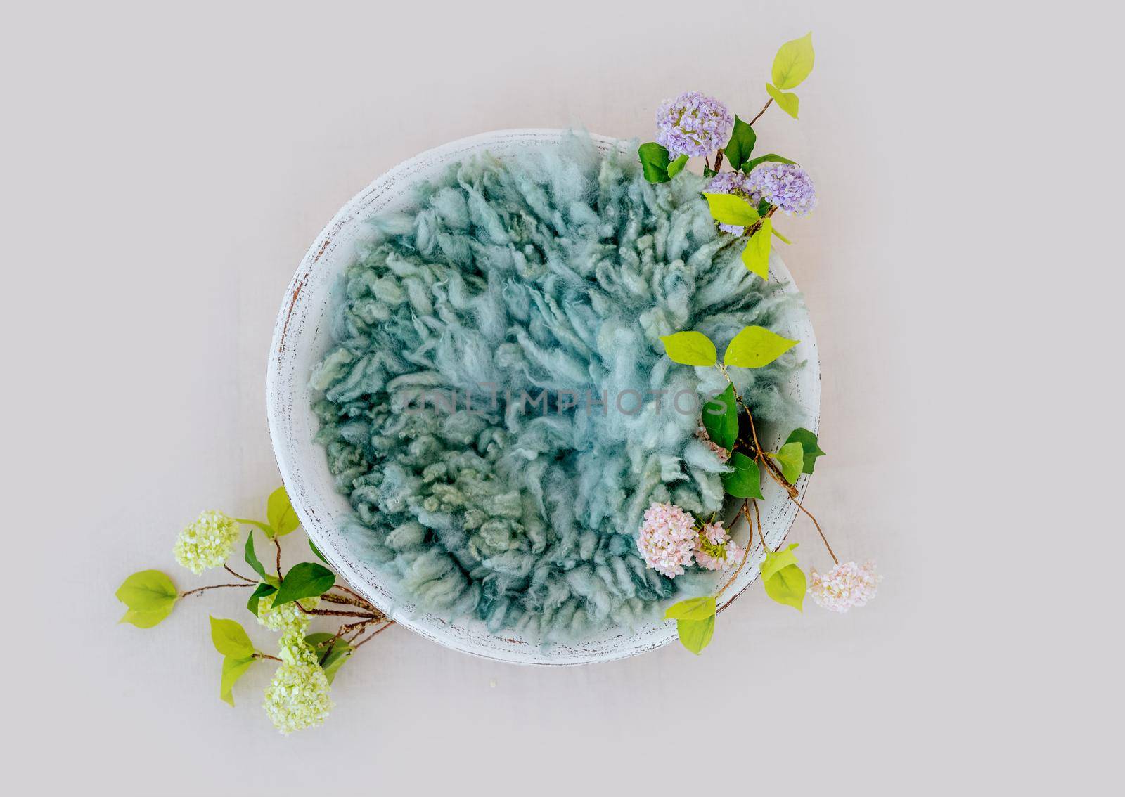 Wooden stylized white furniture bed basin with blue fur and flowers for newborn photoshoot. Designed decoration object for infant studio photo isolated on grey background with copyspace