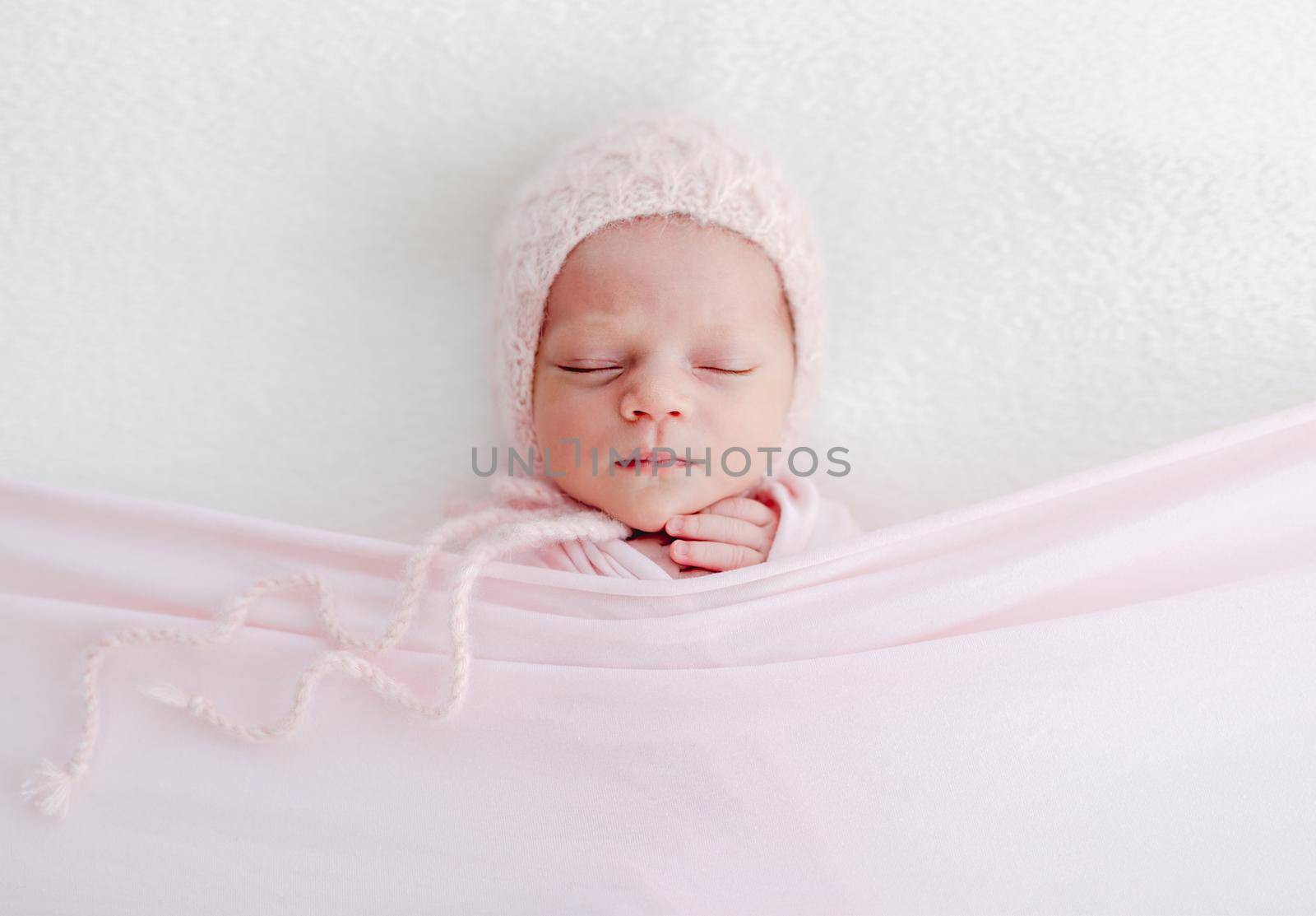 Sleeping newborn baby girl wrapped in white blanket