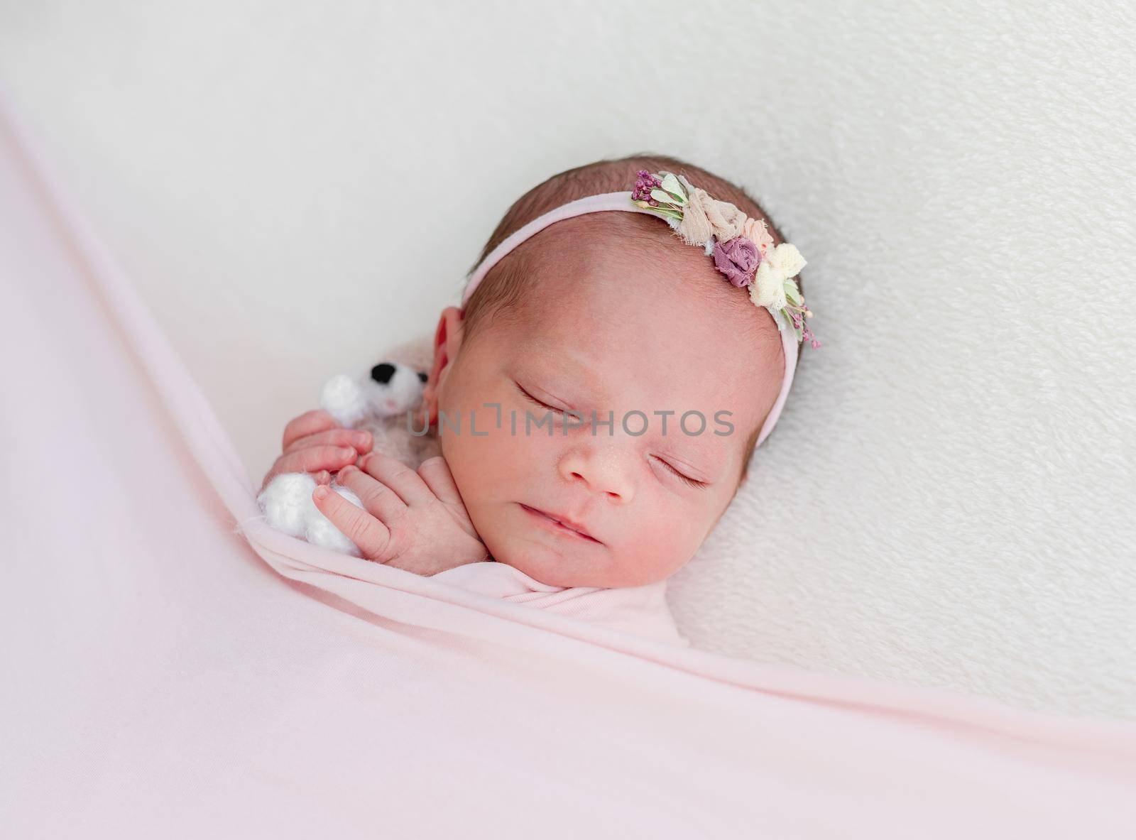 Sleeping newborn baby girl wrapped in white blanket