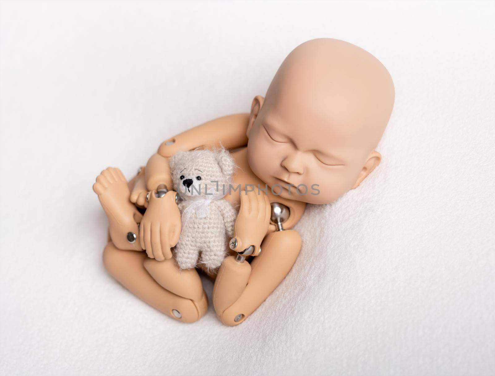 Cute toy of newborn baby with teddybear for photo practice, isolated on white background