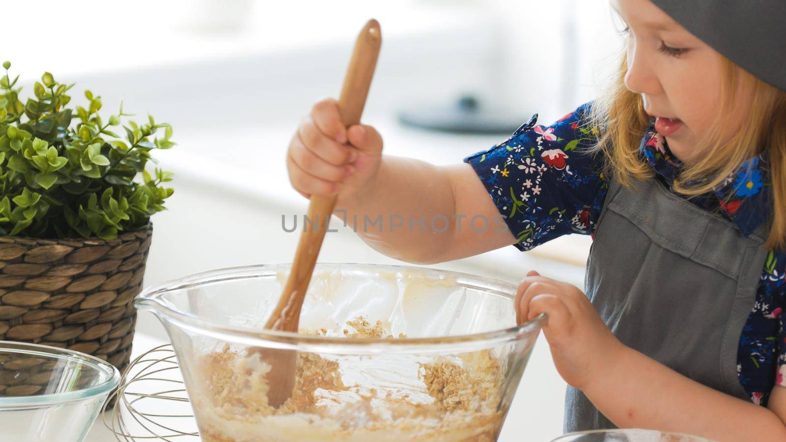 Girl baker mixes the mixture for cookies with a whisk, close up