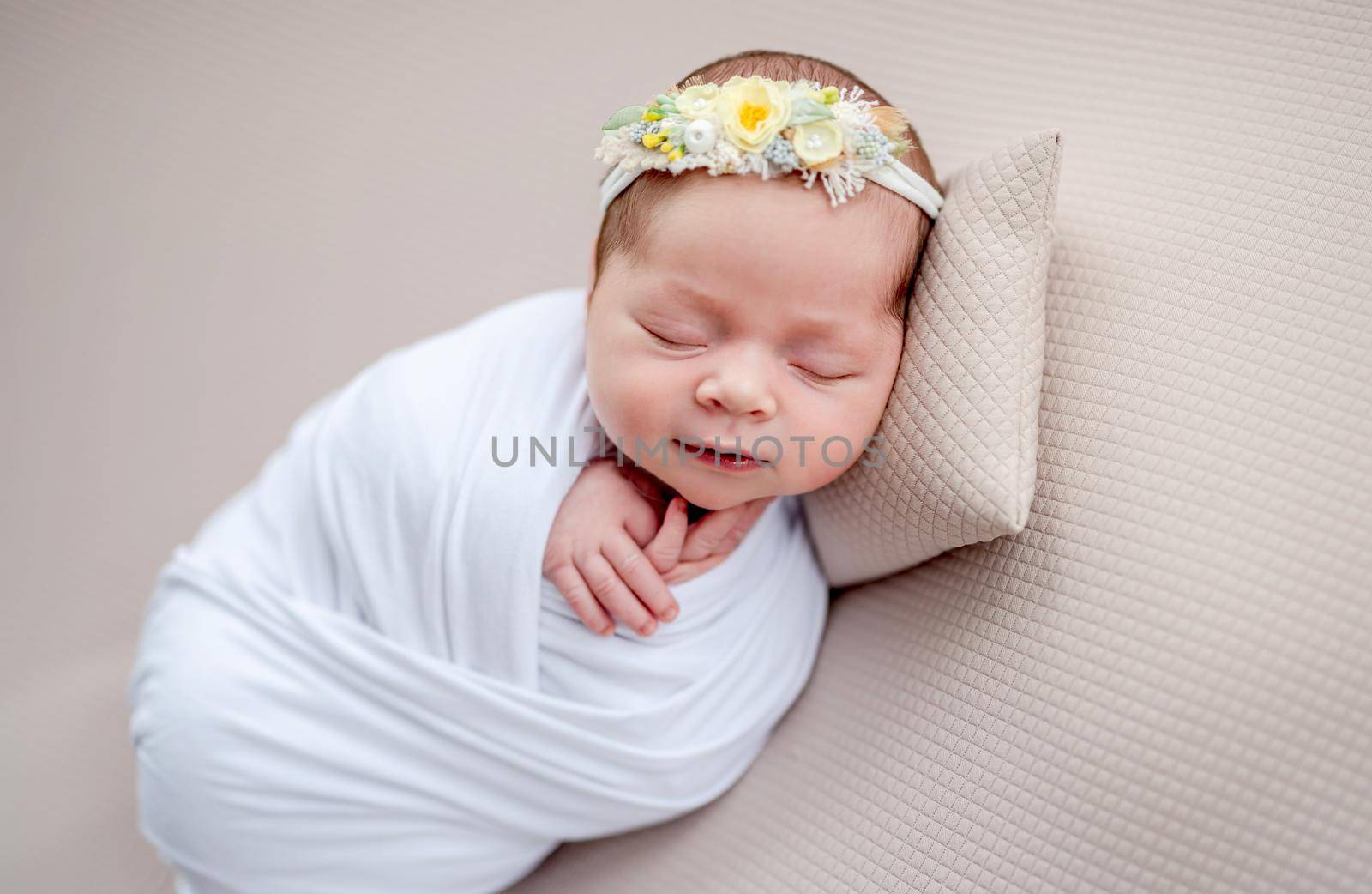 Smiling newborn in floral rim sleeping on tiny pillow