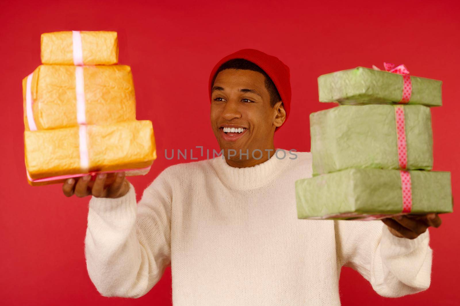 Christmas mood. A dark-skinned excited young guy with a gift boxes in hands