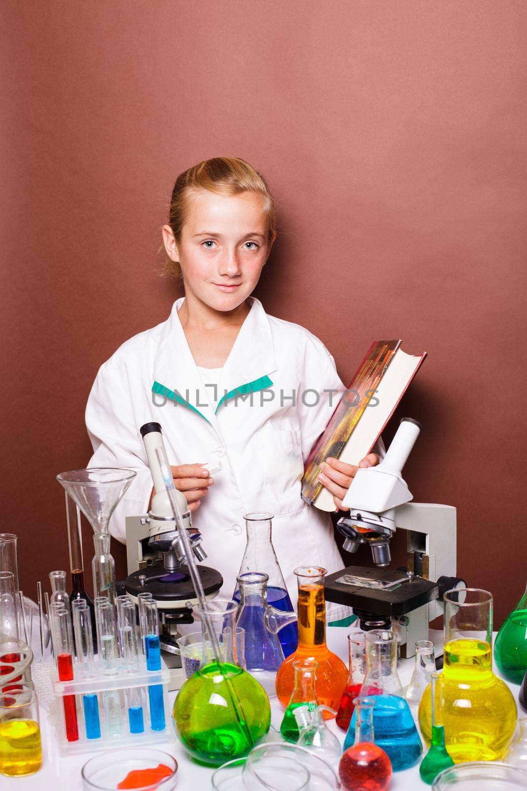 Schoolgirl with chalk standing near blackboard in the laboratory classes in chemistry