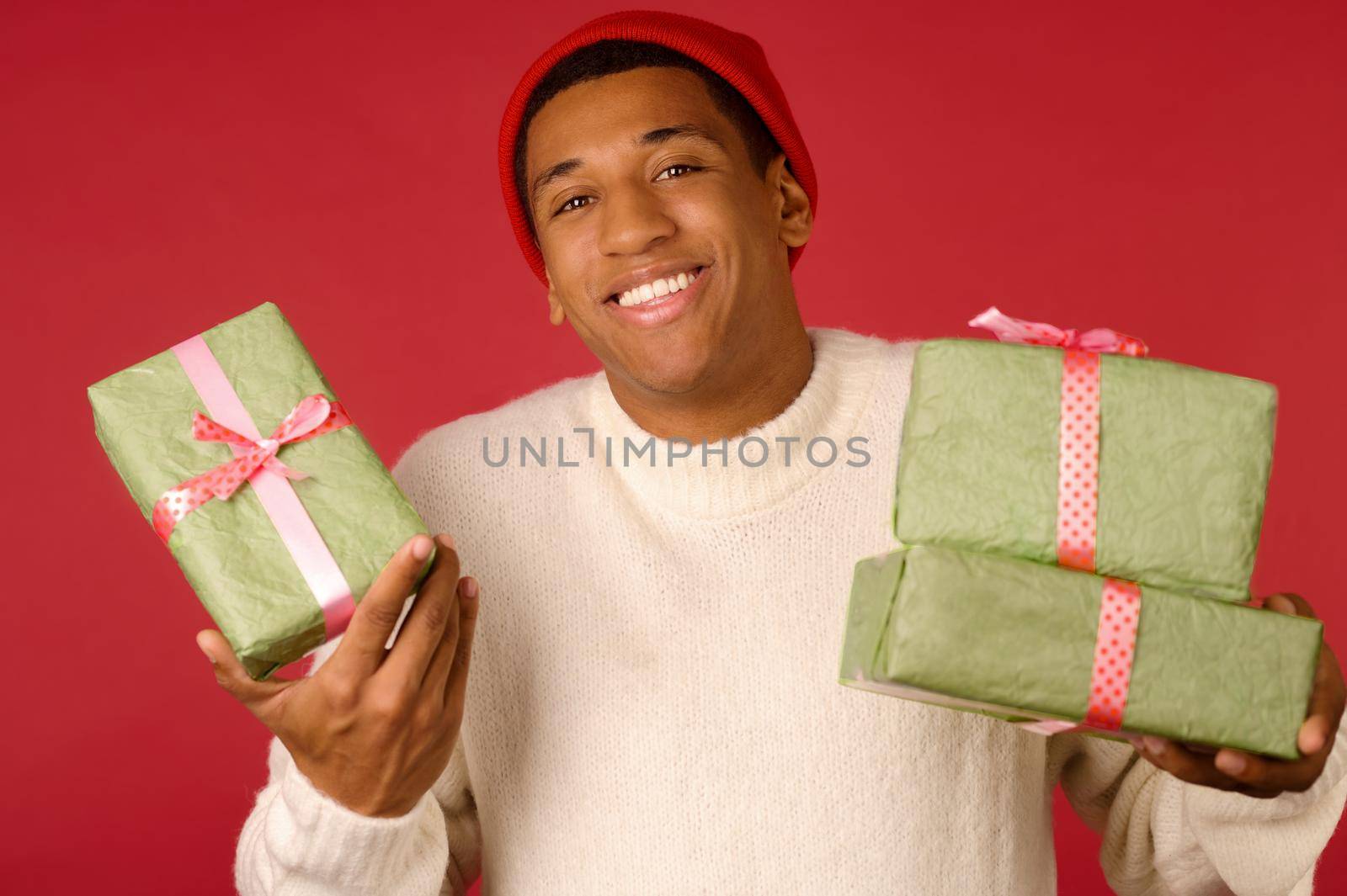 Young guy in santa hat holding gifts by SDM_Prod_Studio