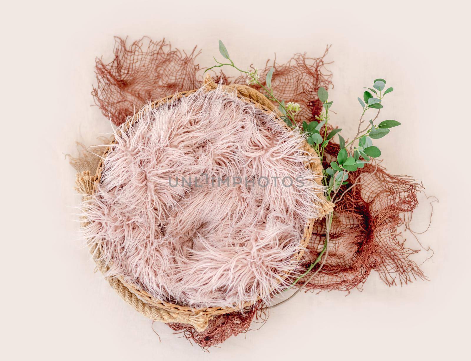 Beautiful backdrop for newborn photosession with flowers hydrangea. Digital composite with basin filled with knitted blanket isolated on light pink background. Top view