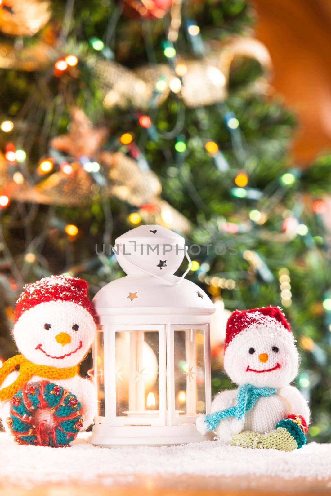 Knitted snowmen and Christmas lantern-candlestick - home decorations on the snow