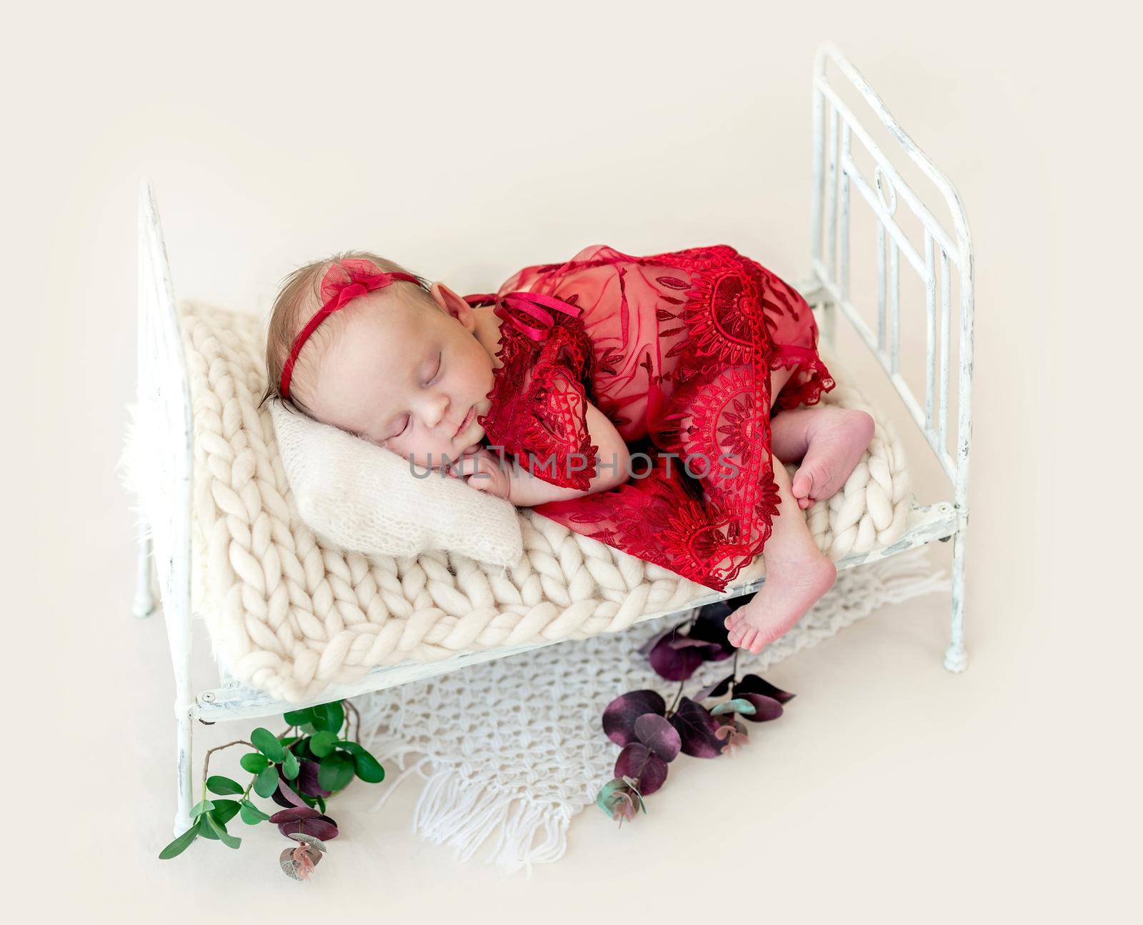 Sleeping newborn baby girl in a red dress