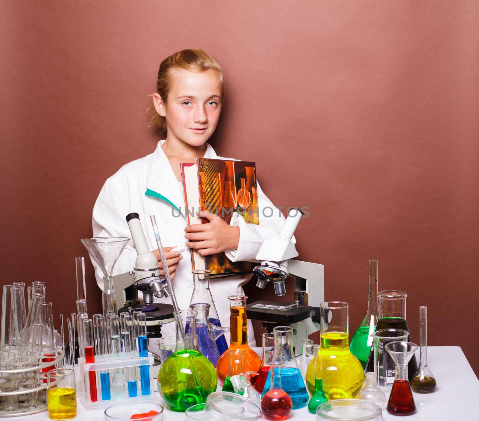Schoolgirl standing near blackboard in the laboratory classes in chemistry. Focus on the microscope