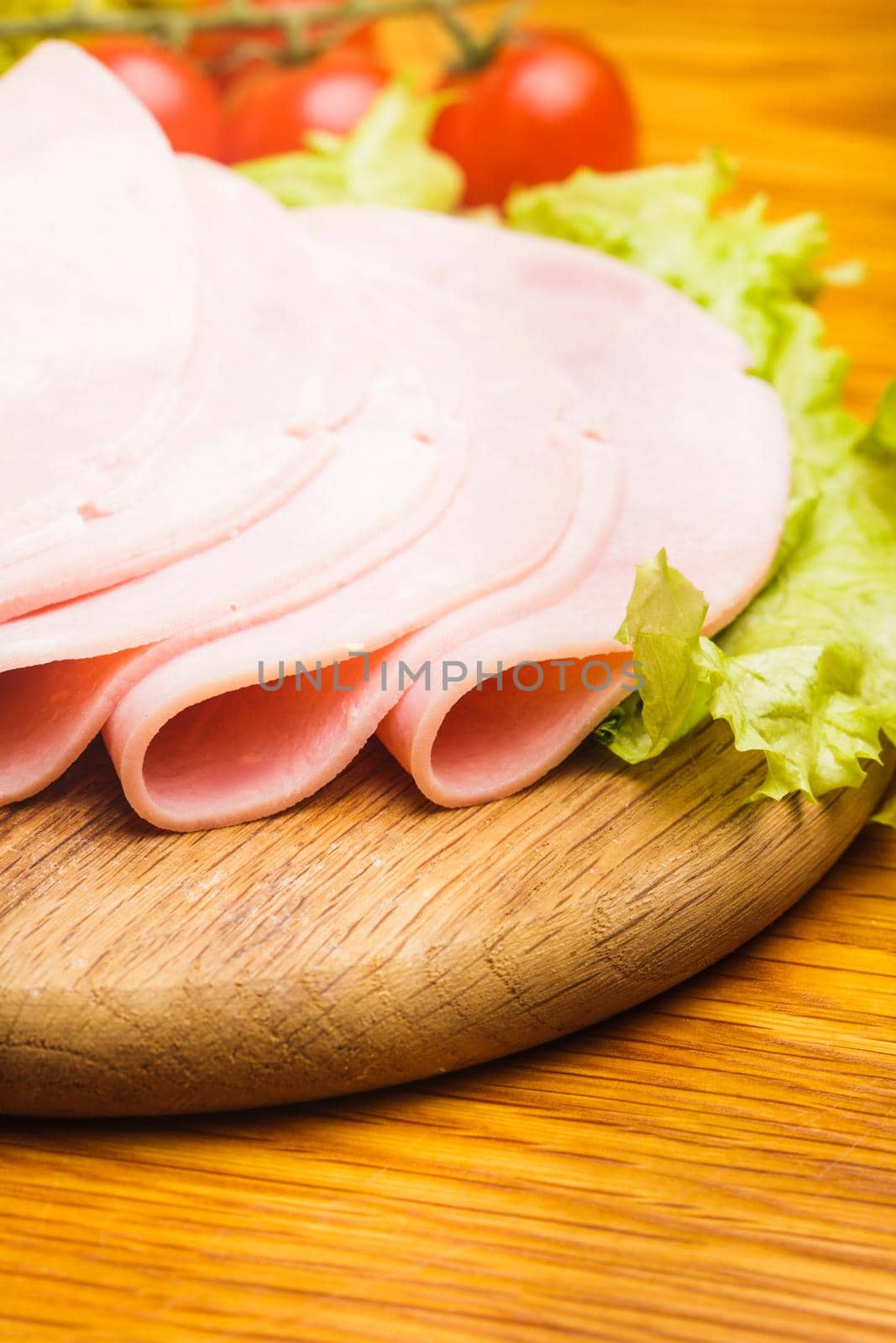 Fresh ham slices with lattuce and cherry tomato on the wooden board