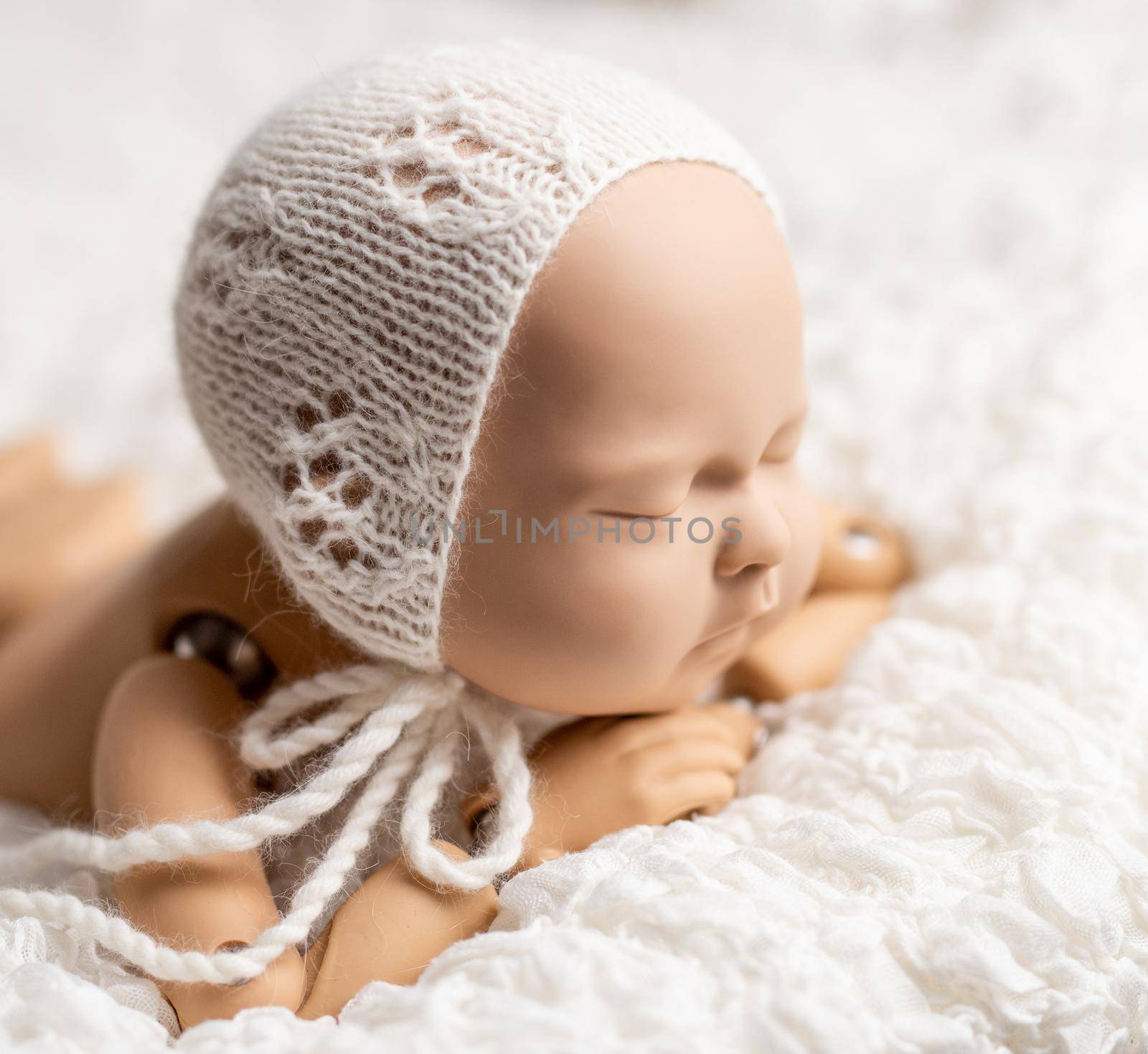 Realistic plastic figure of newborn child for photographing practice, with head on hands