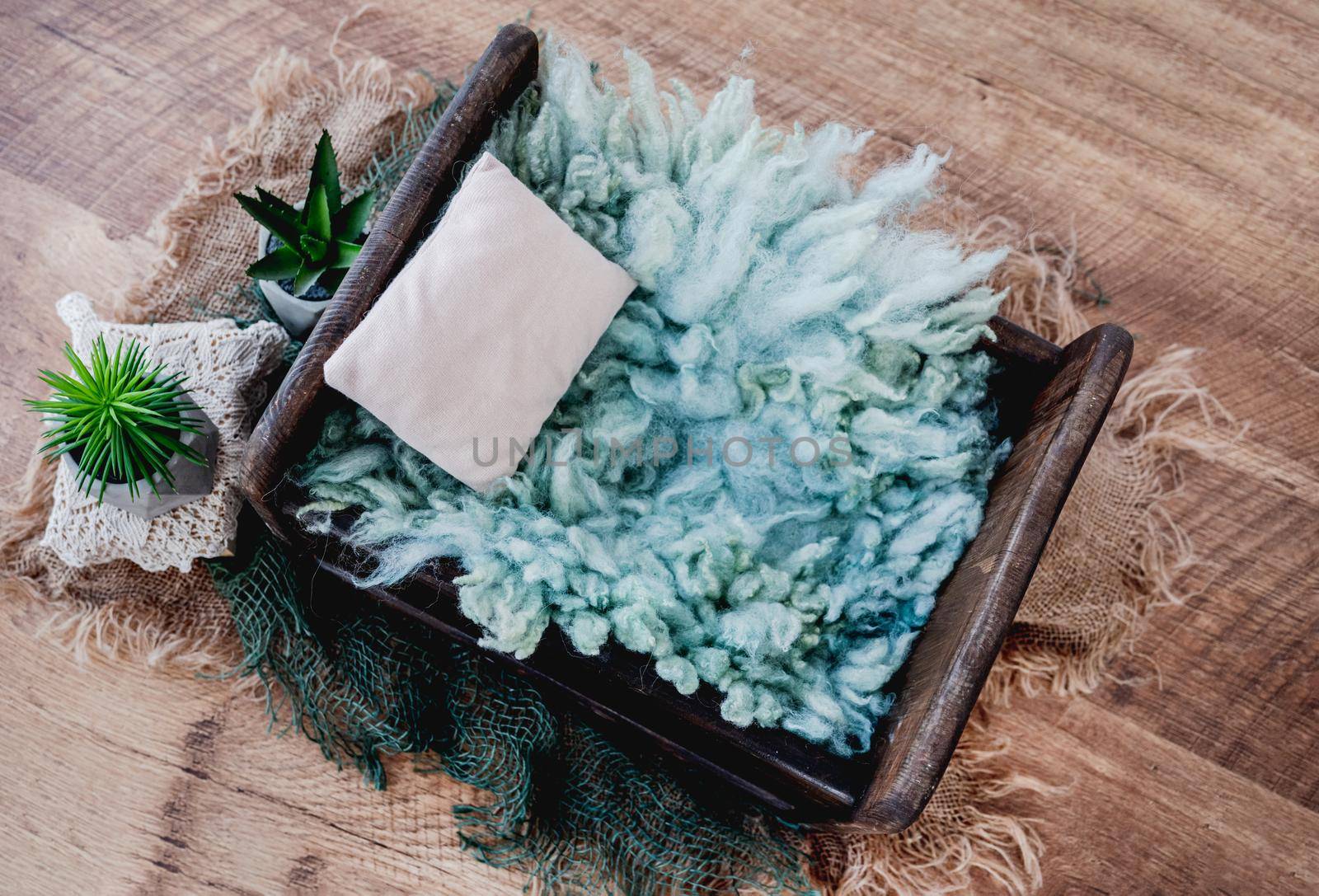 Cute cozy background for newborn photosession with plants. Digital composite with wooden bed filled with light blue fur and standing on sackcloth