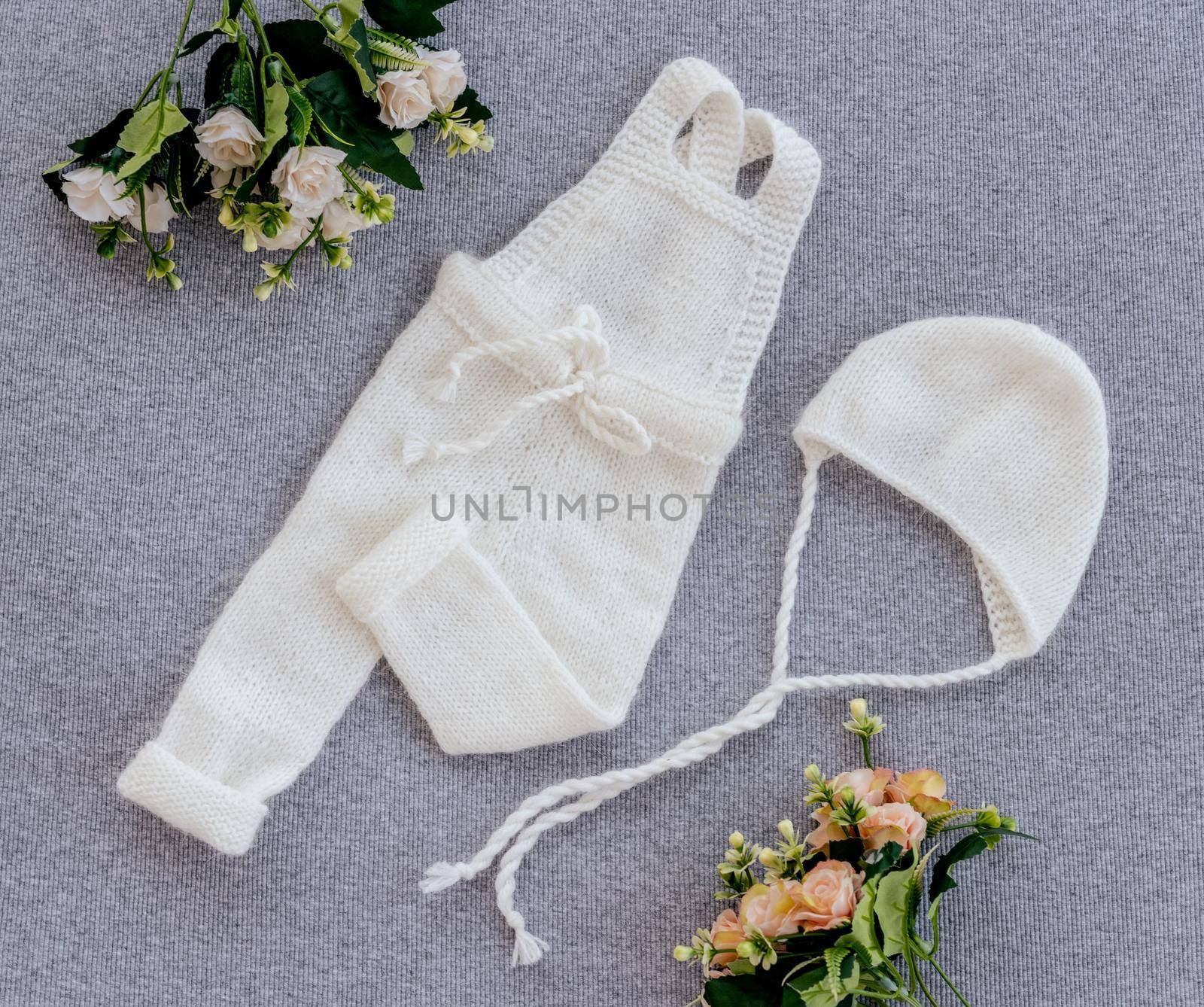 White knitted newborn clothes composition with flowers for infant baby photosession