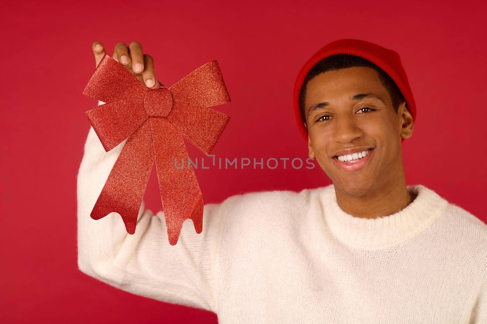 A young dark-skinned man in santa hat feeling joyous by SDM_Prod_Studio