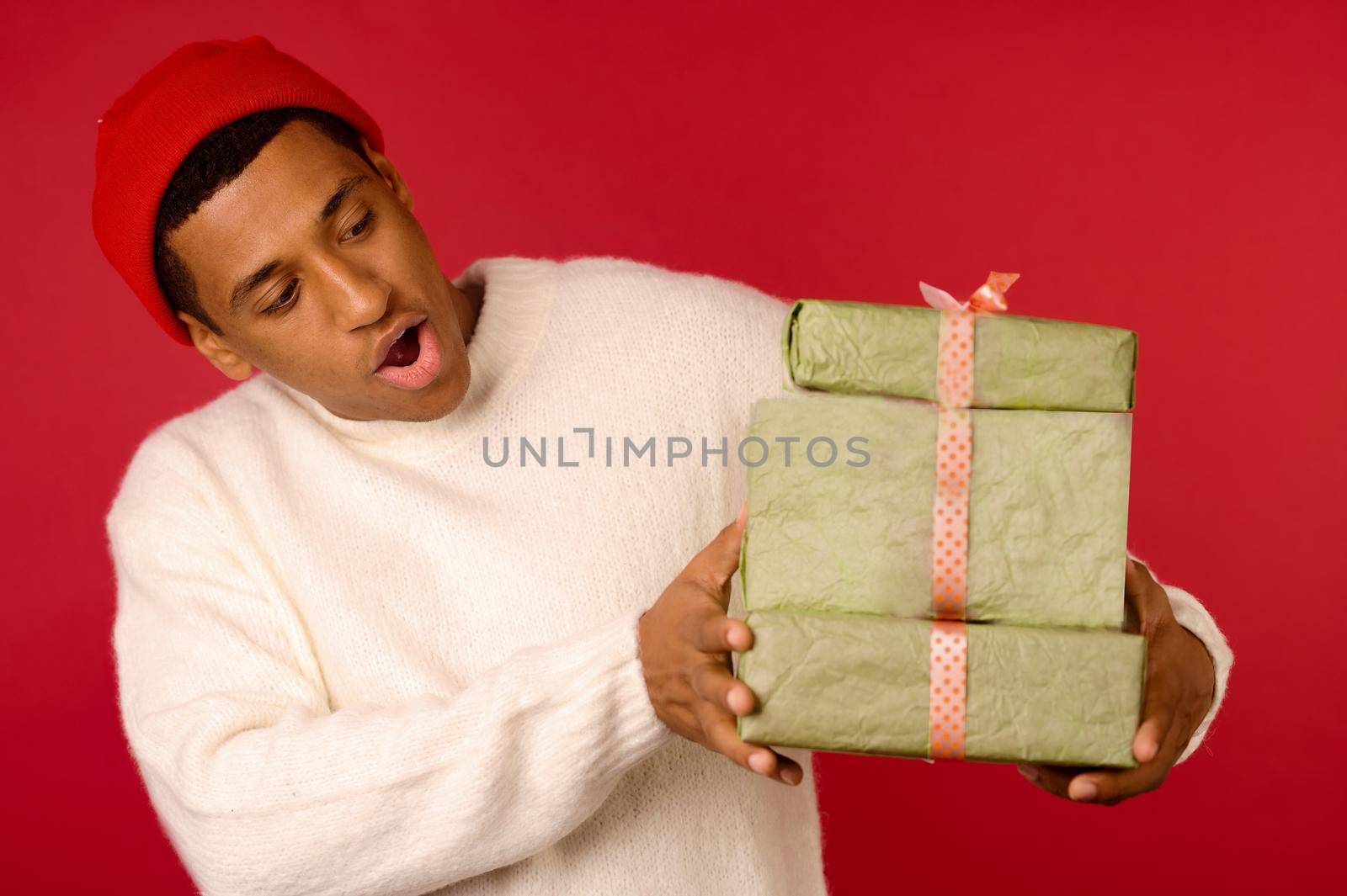 Xmas presents. Smiling dark-skinned young guy with gift boxes in hands