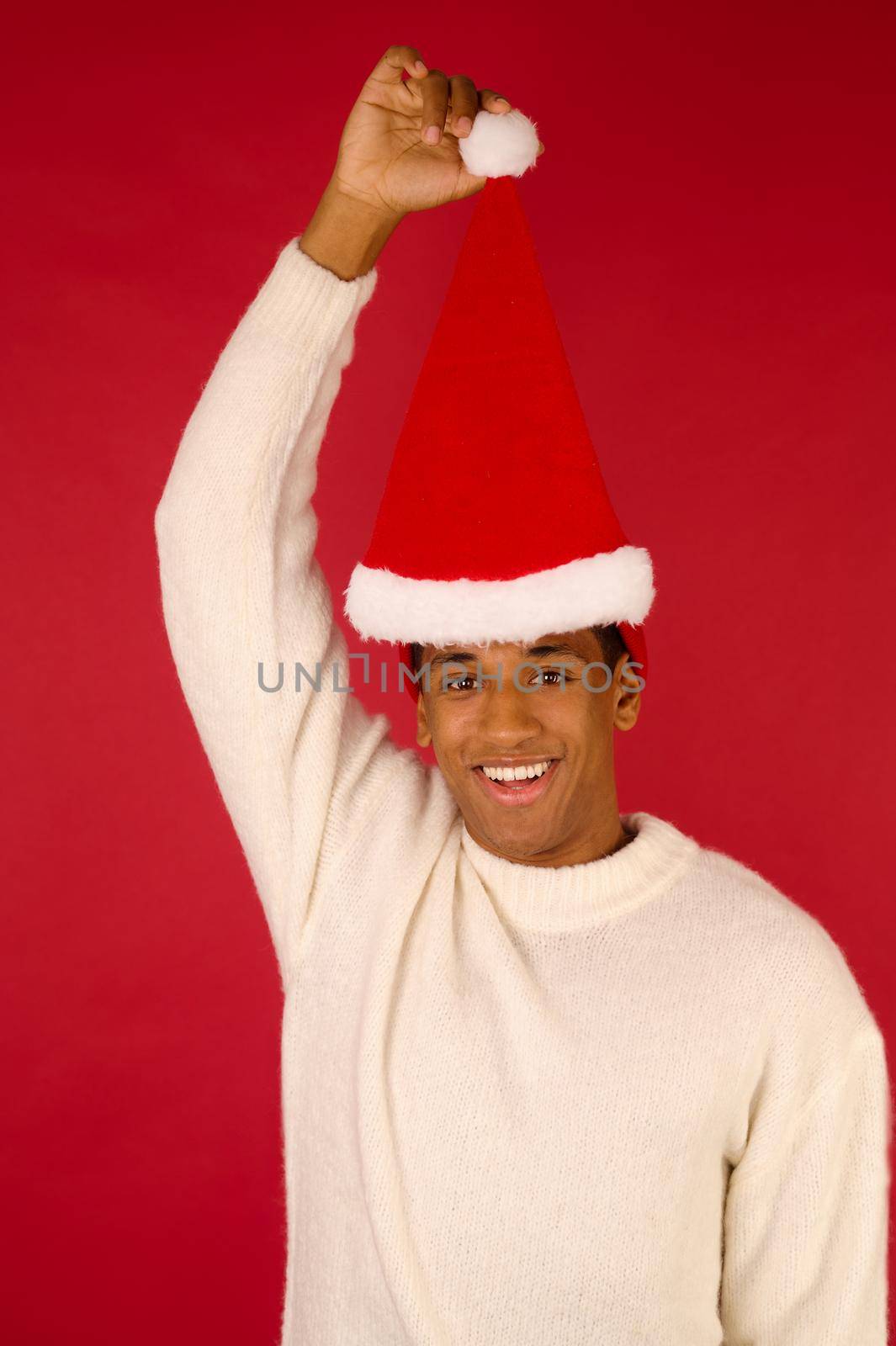 Ready for Xmas. Young smiling guy with santa hat with in hand