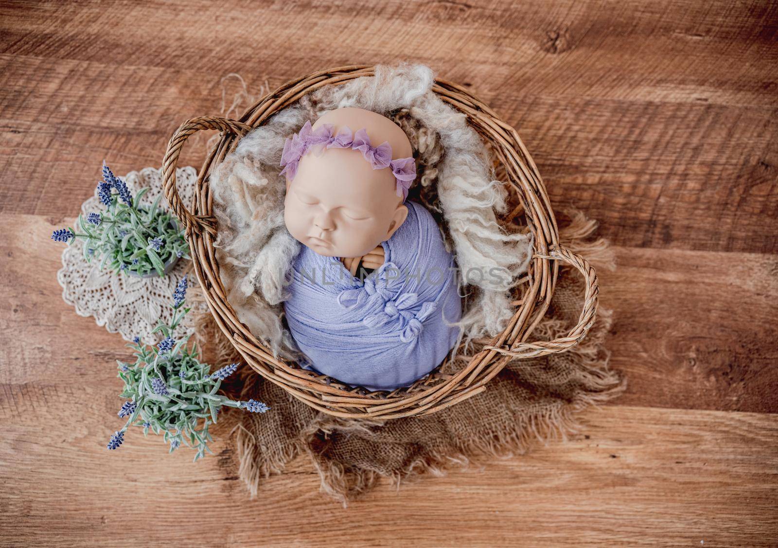 Beautiful background for newborn photosession with flowers and swaddled infant manequen for photographer trainings. Digital composite with baby doll model