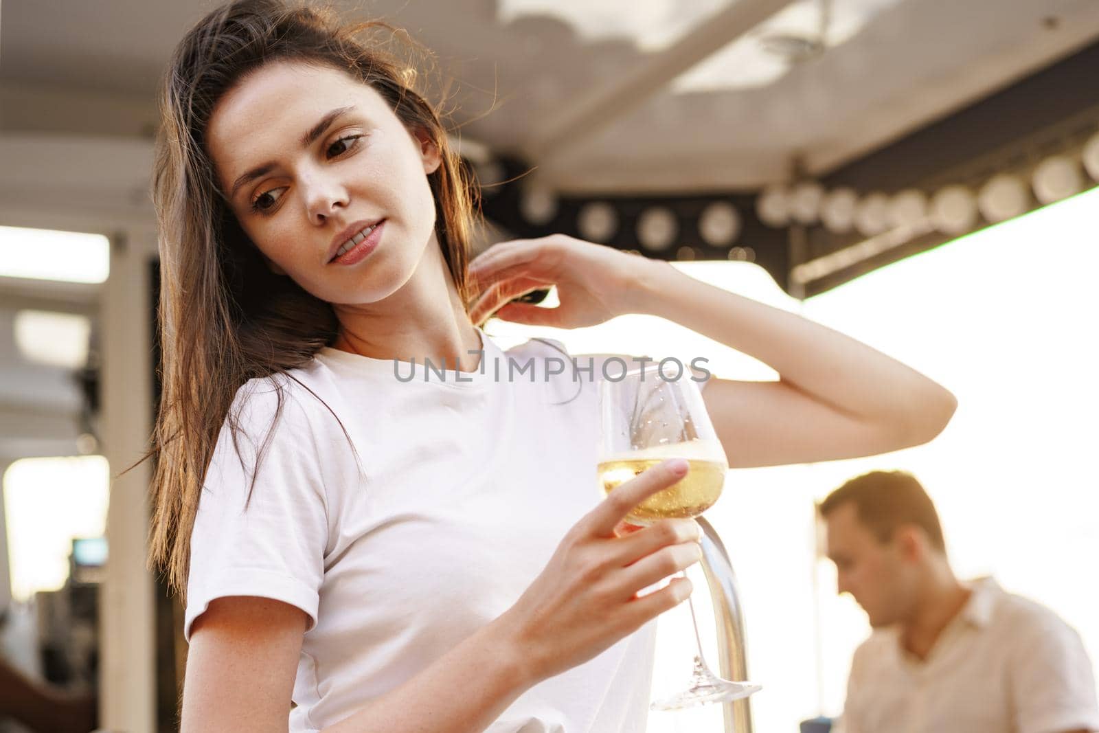 Young woman holding a wineglass and sitting on deck of sailing yacht by Fabrikasimf