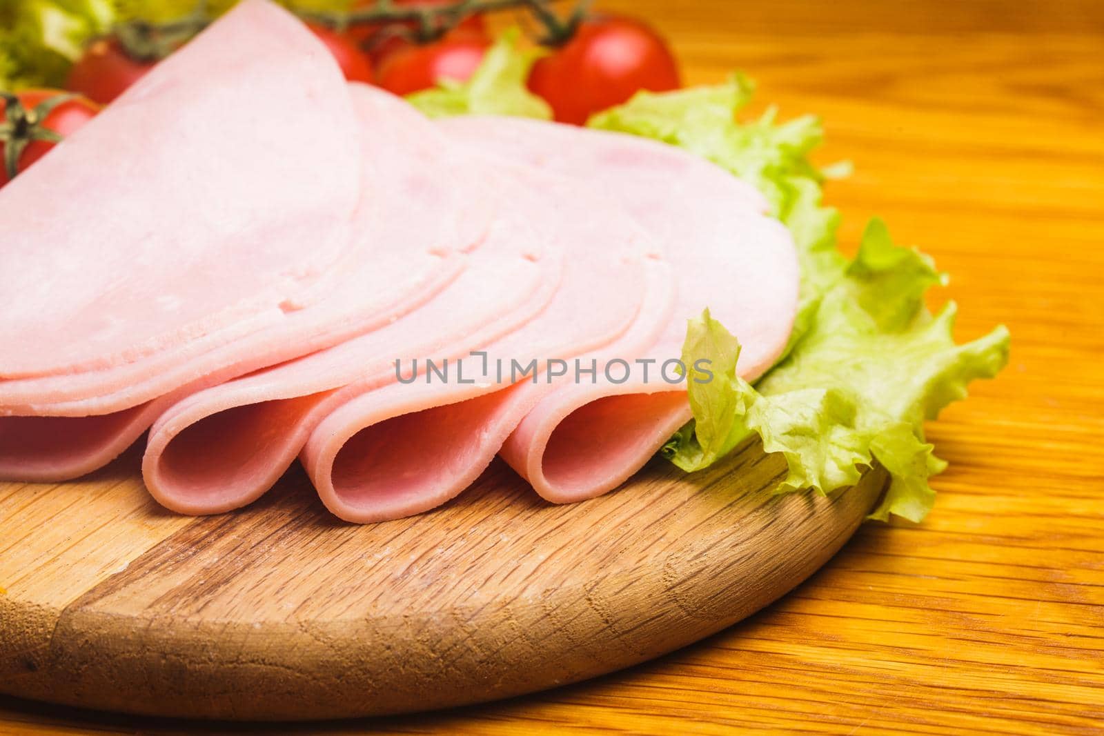 Fresh ham slices with lattuce and cherry tomato on the wooden board