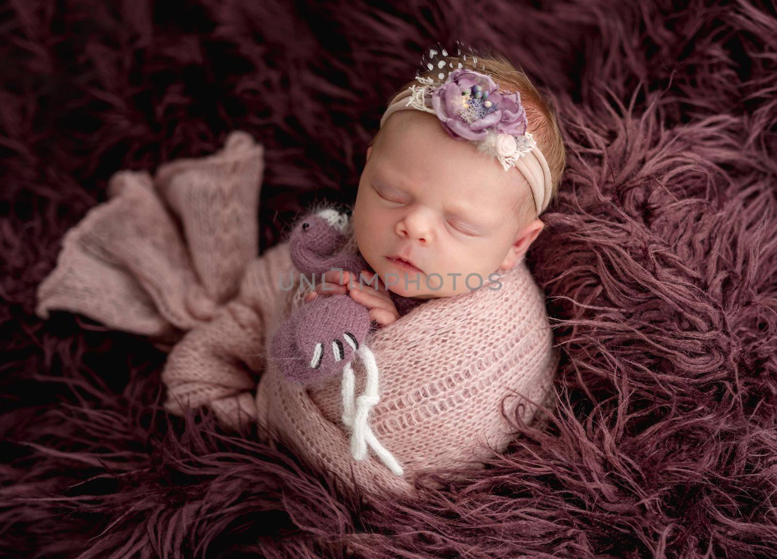 Sleeping newborn with floral rim hugging tiny toy