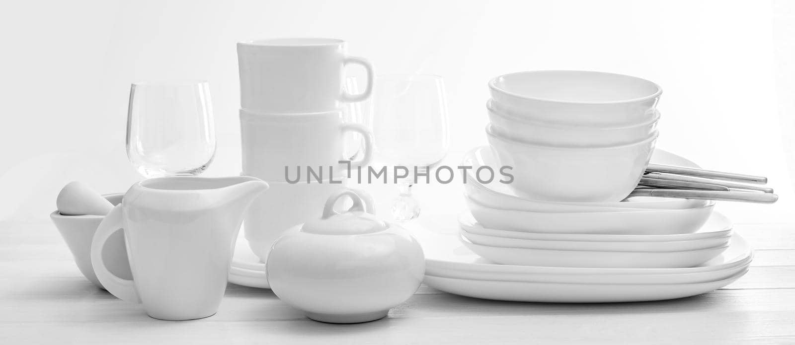 Set of clean white plates and cutleries on light background