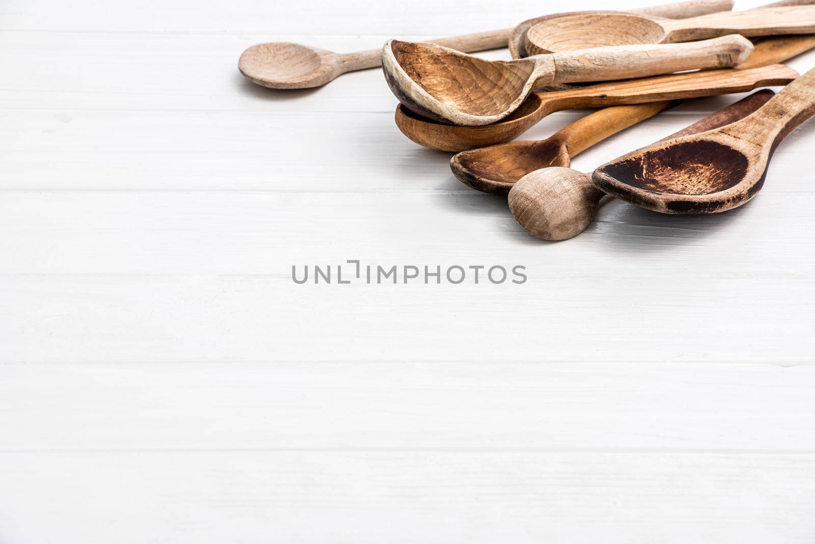 Big wooden natural spoons on white wooden background with free space for text, copyspace