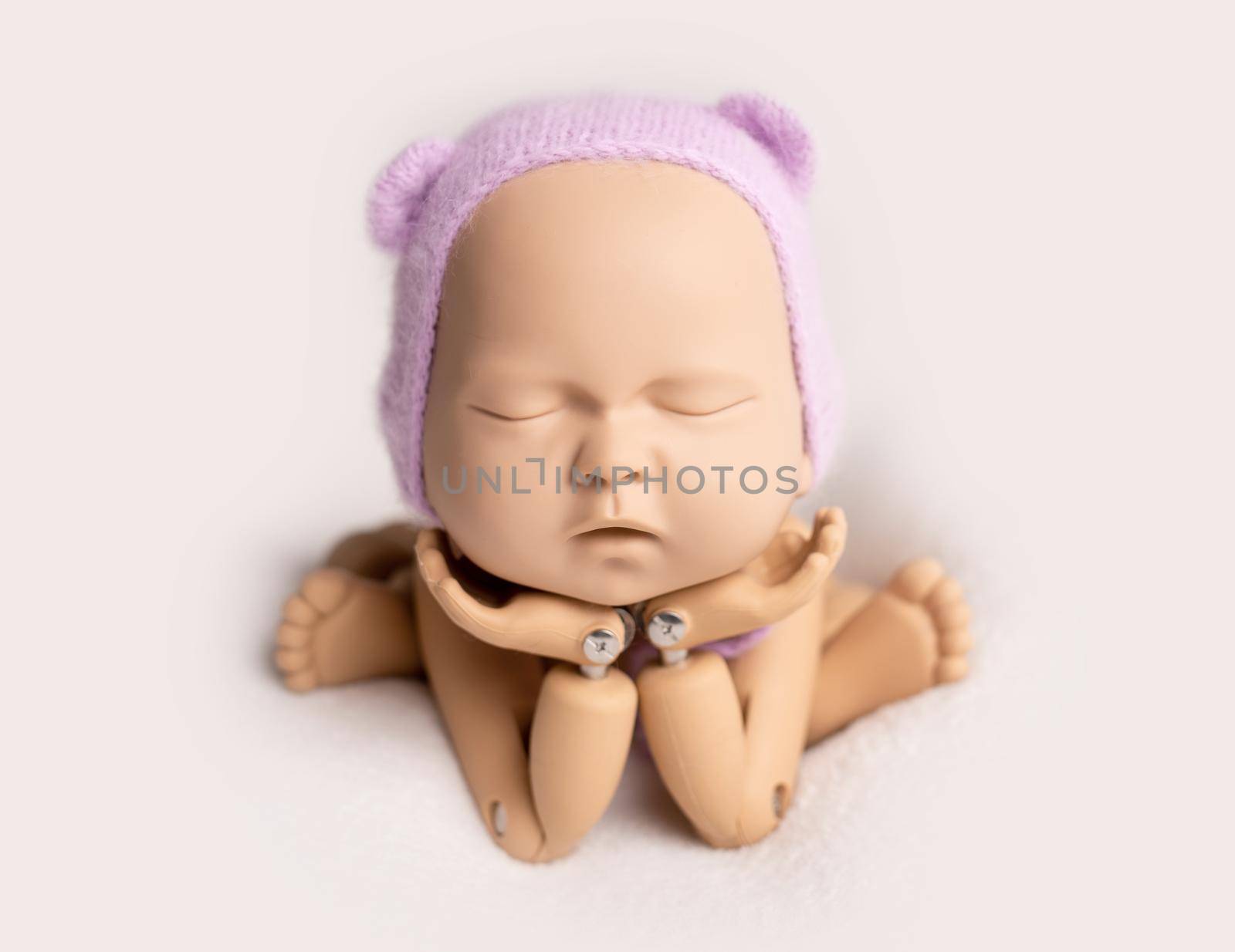 Plastic mannequin of baby, made for posing, in frog stand, isolated