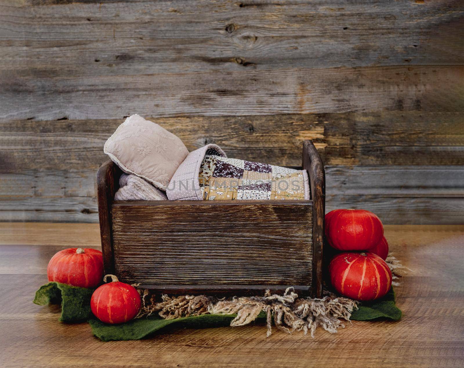 Tiny wooden bed for newborn baby photoshoot decorated with autumn pampkins. Studio handmade scene for halloween infant child photos indoors