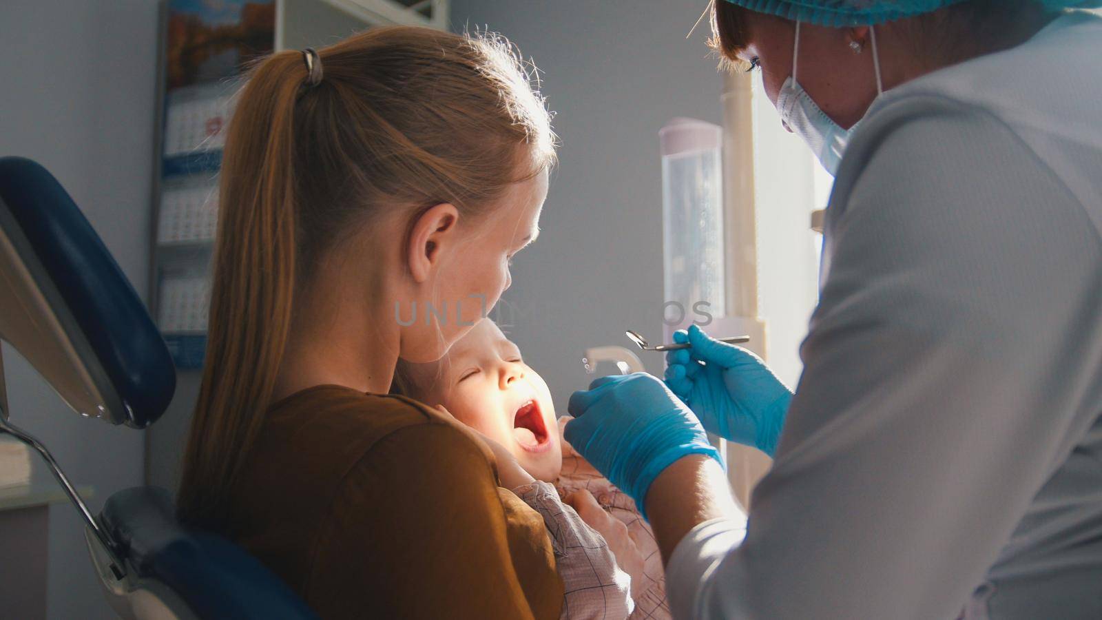 Girl, her mom and the dentist in the dental office, the stomatologist advising with a special toy by Studia72