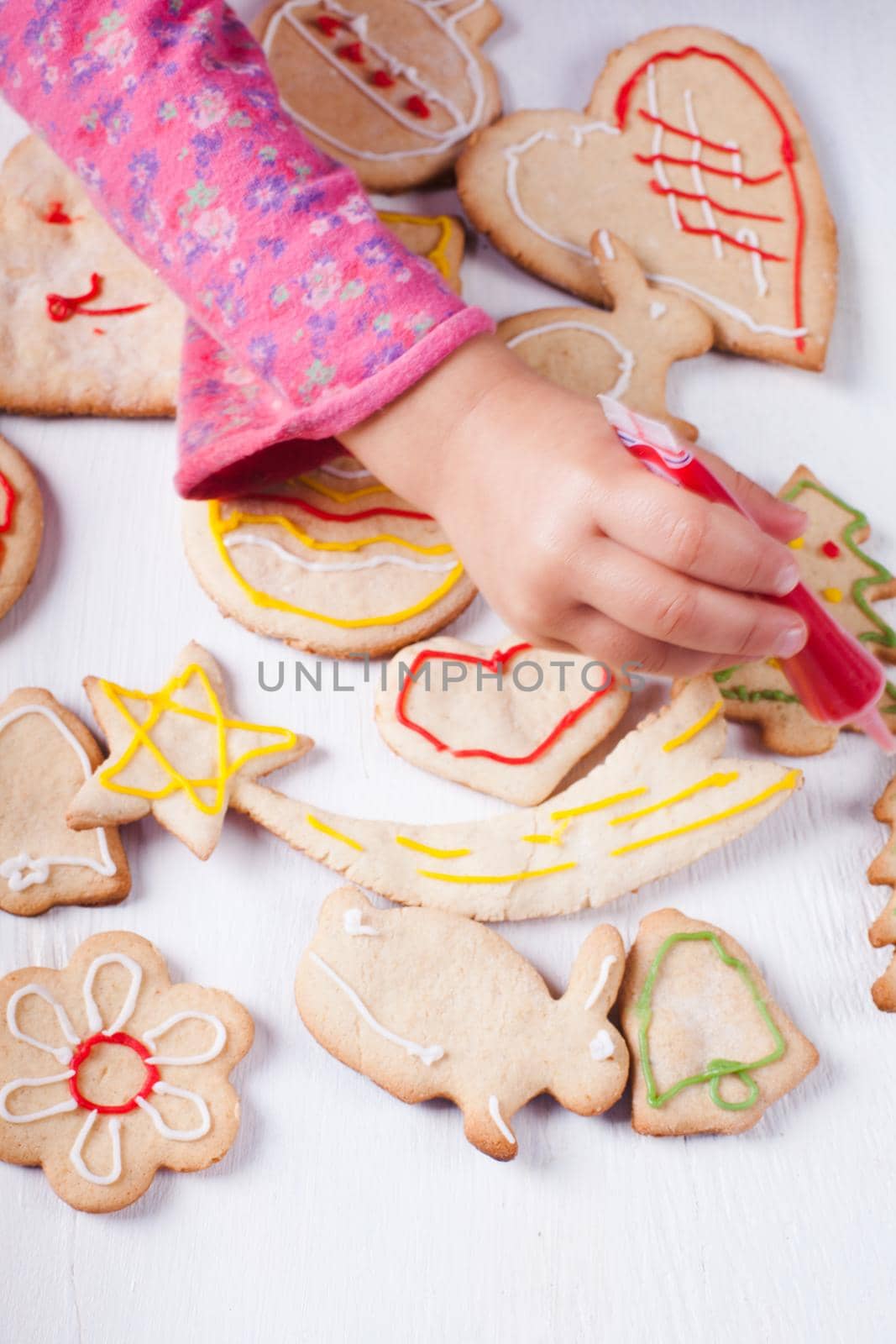 Hands of little girl, who draws on gingerbread cookies