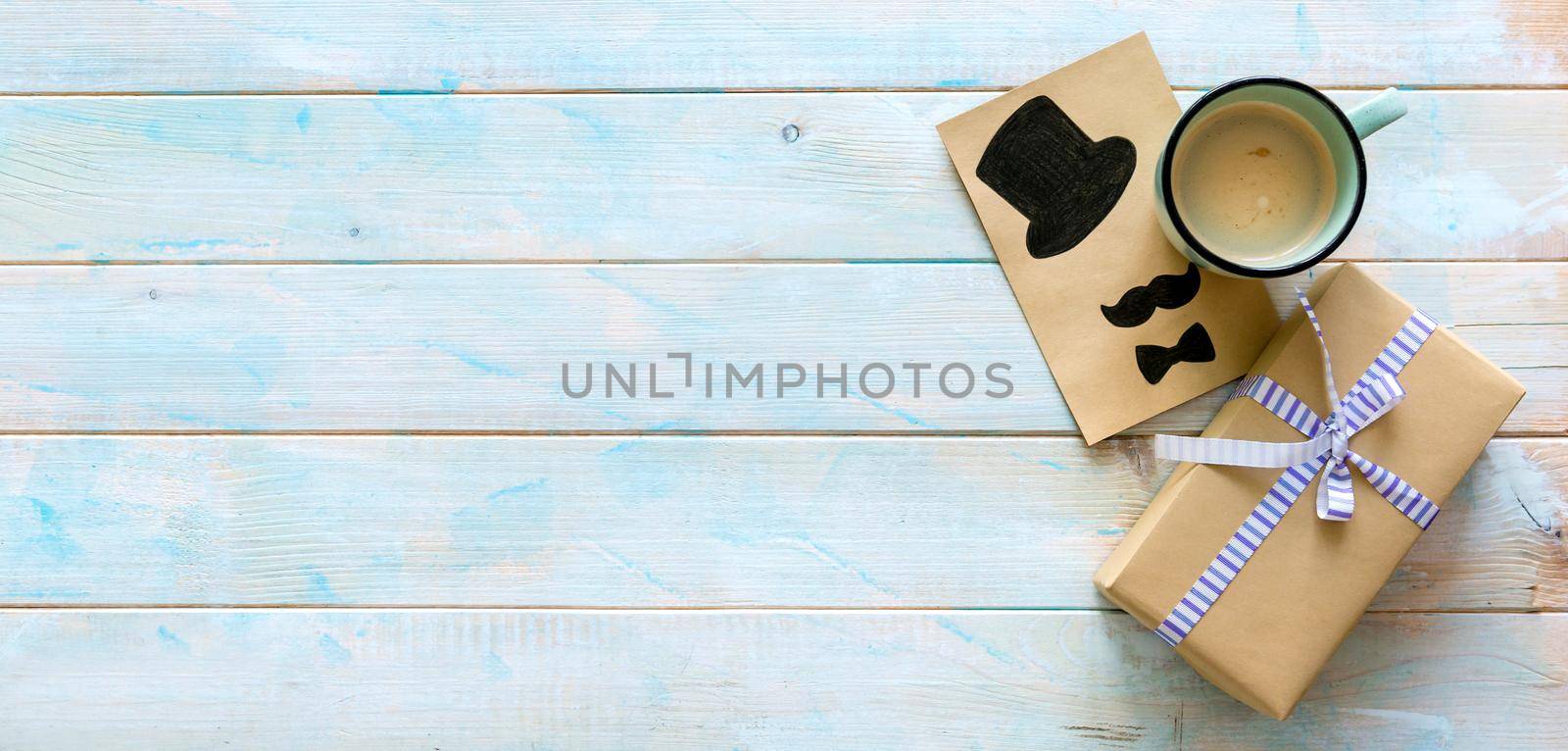 Happy father's day concept. Top view of small gift wrapped in brown craft paper with cup of cacao and greeting card