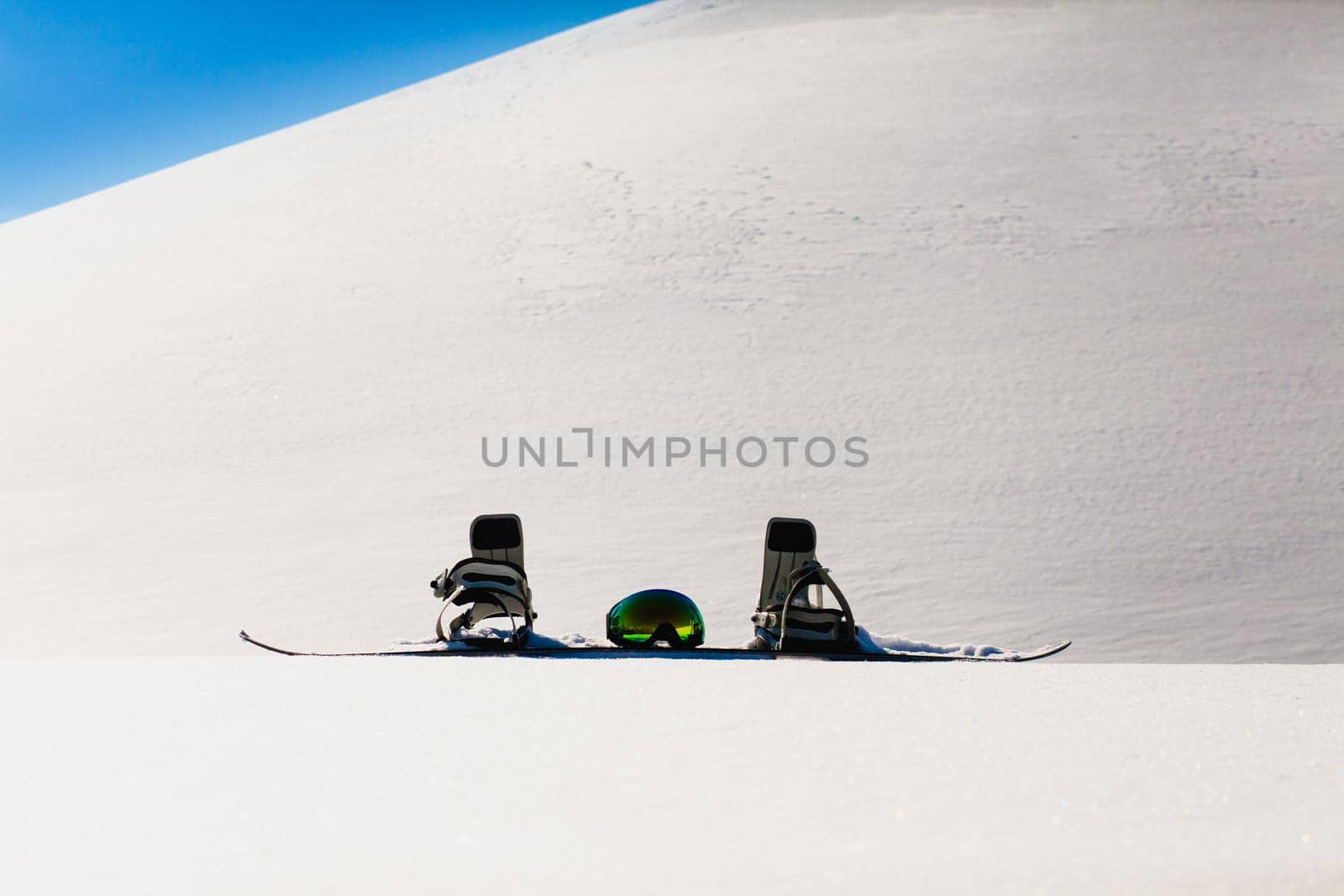 Snowboard and ski googles laying on a snow near the freeride slope by Gennadii_Chebeliaev