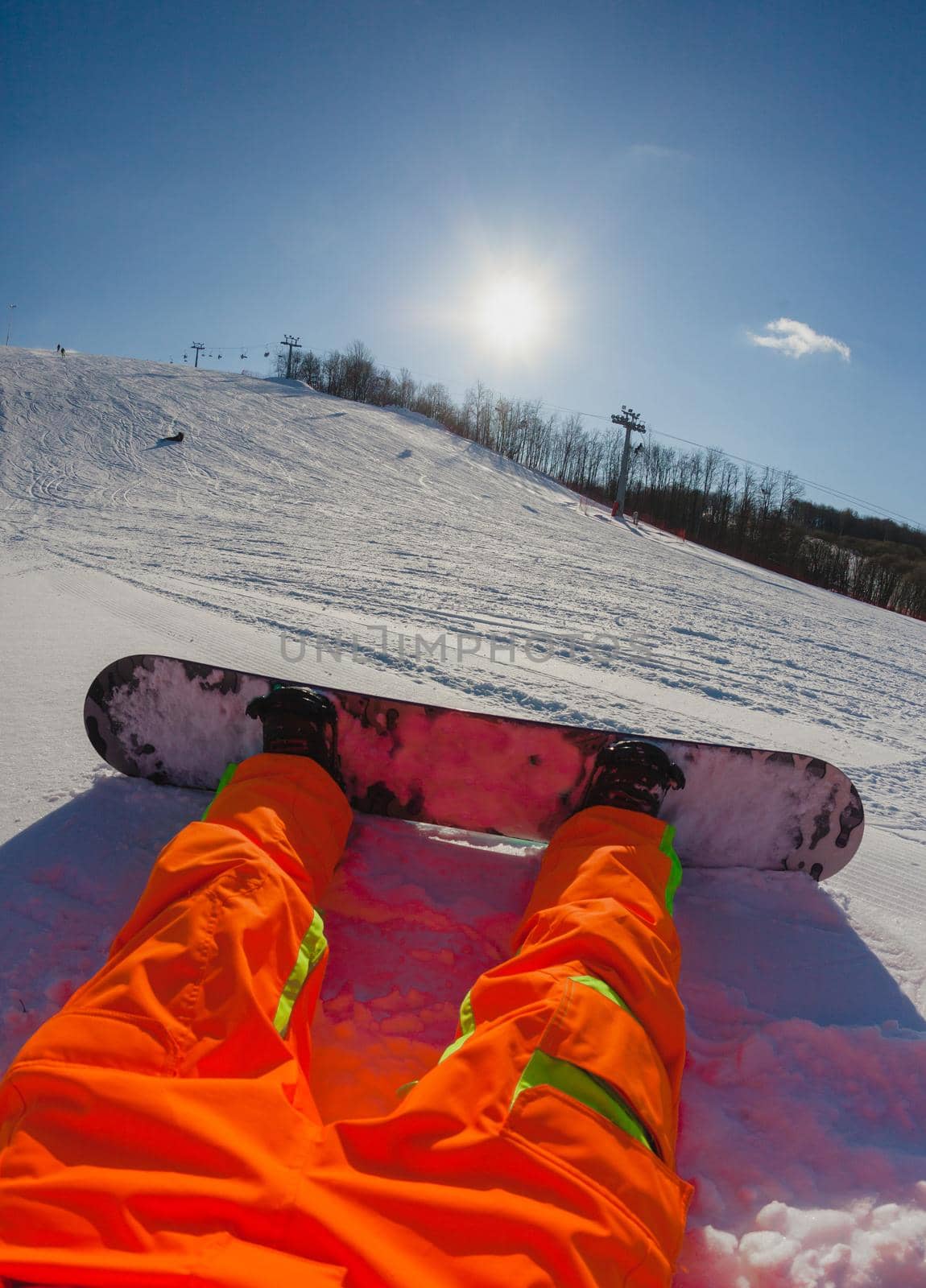 Point of view shot of a male snowboarder sitting on the snow on the slope relaxing after riding