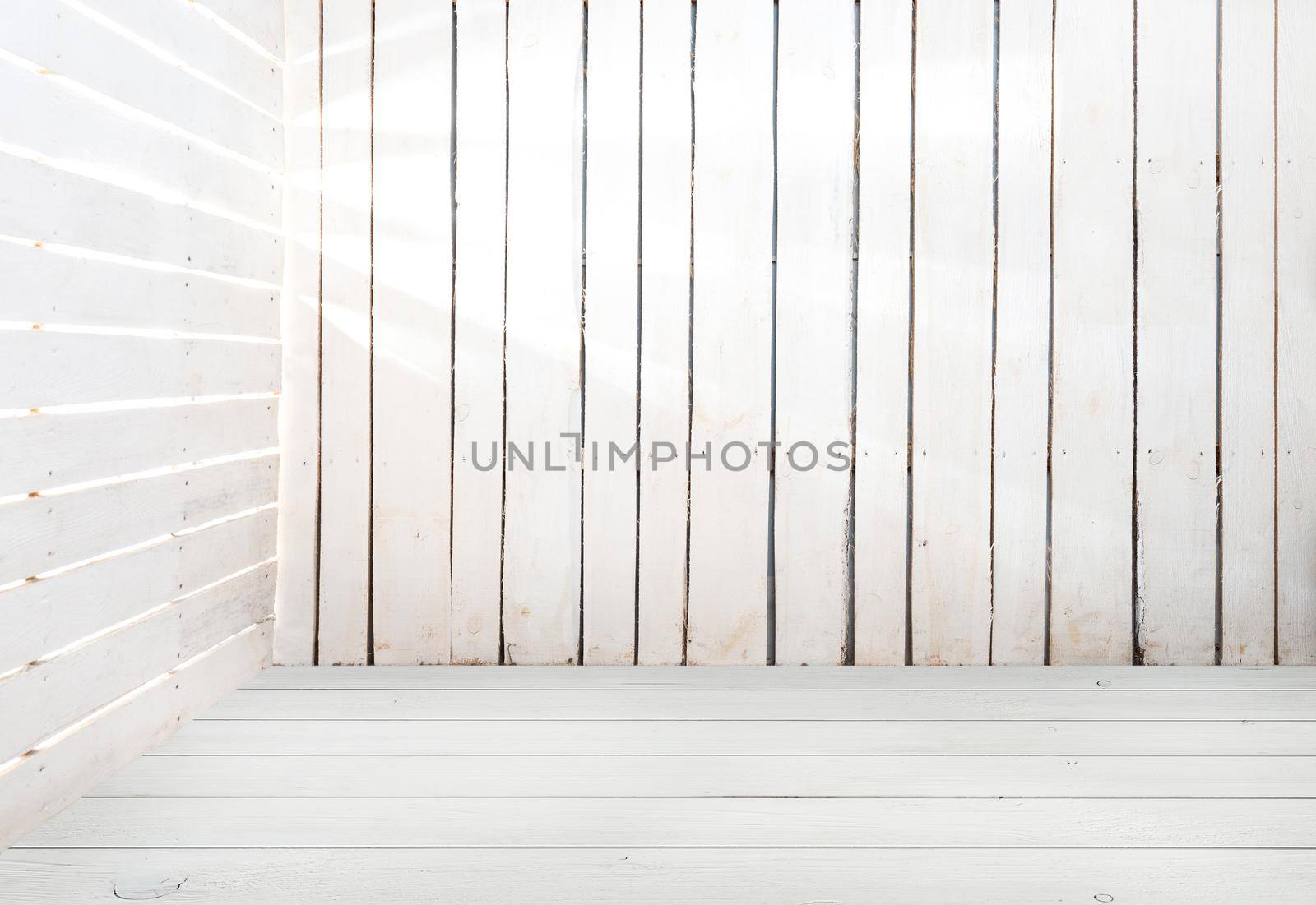 empty white wooden room with light in slits between planks