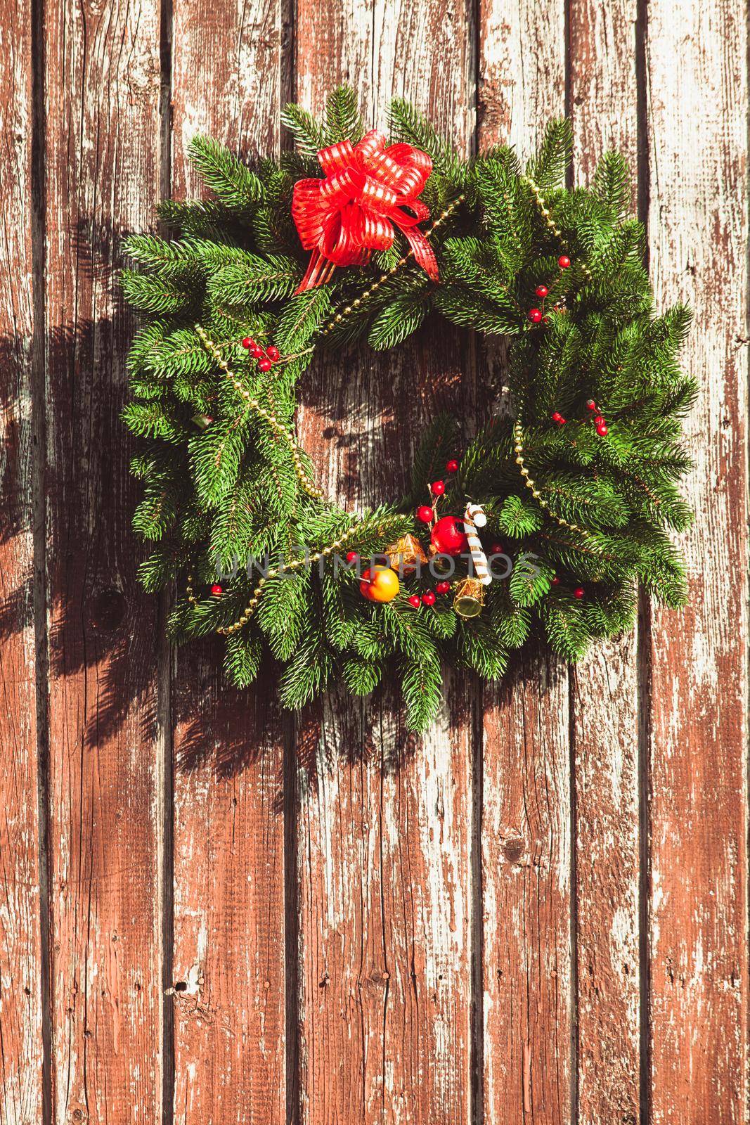 Christmas wreath with decorations on the shabby wooden door.